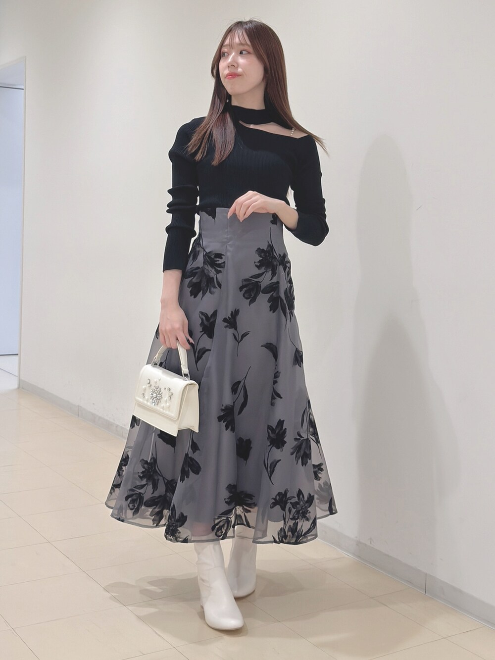 ブラック系のニット/セーター、グレー系のスカート、ホワイト系のショルダーバッグを着用したレディースの冬コーディネートの3枚目の写真