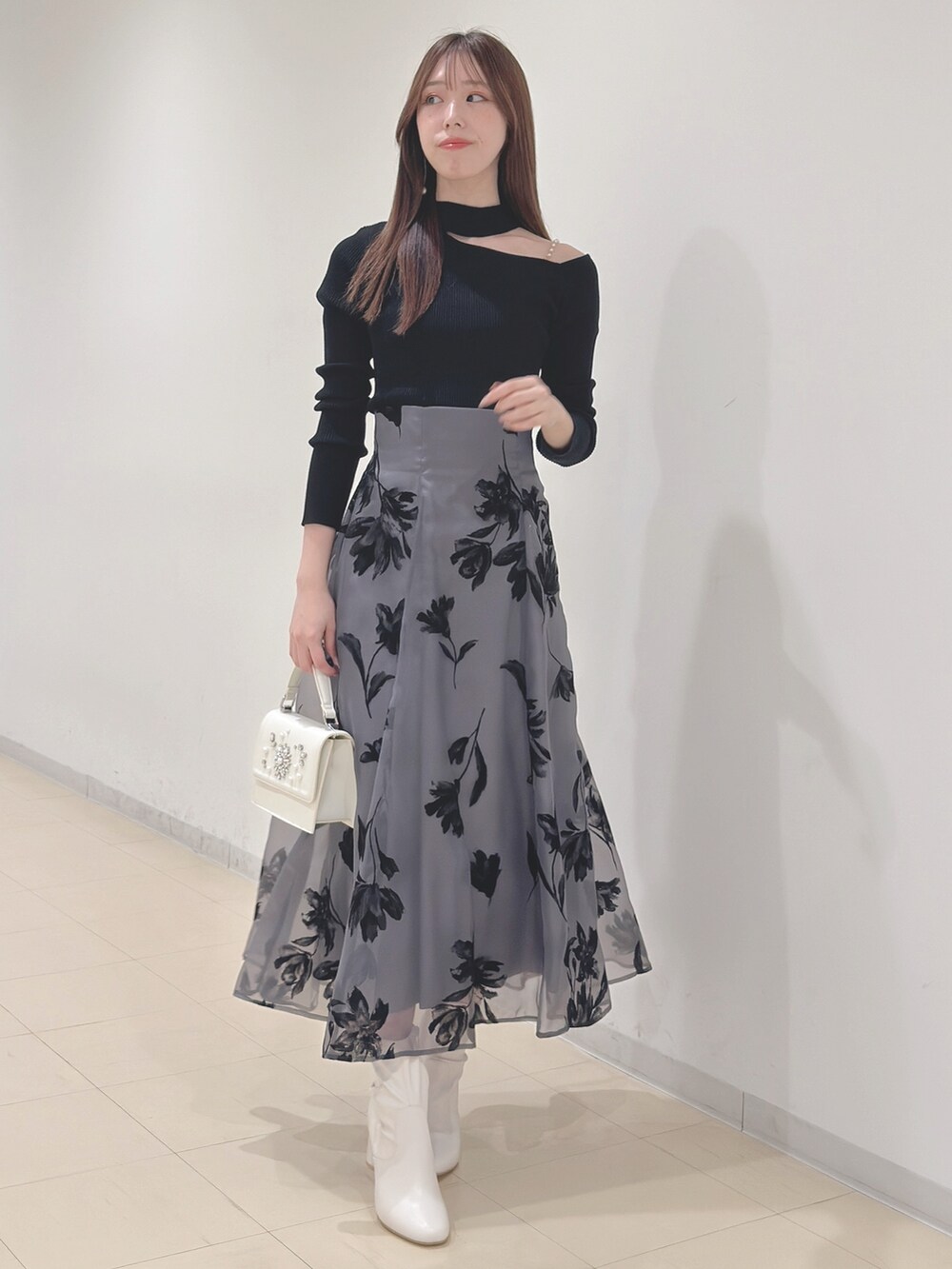 ブラック系のニット/セーター、グレー系のスカート、ホワイト系のショルダーバッグを着用したレディースの冬コーディネートの2枚目の写真