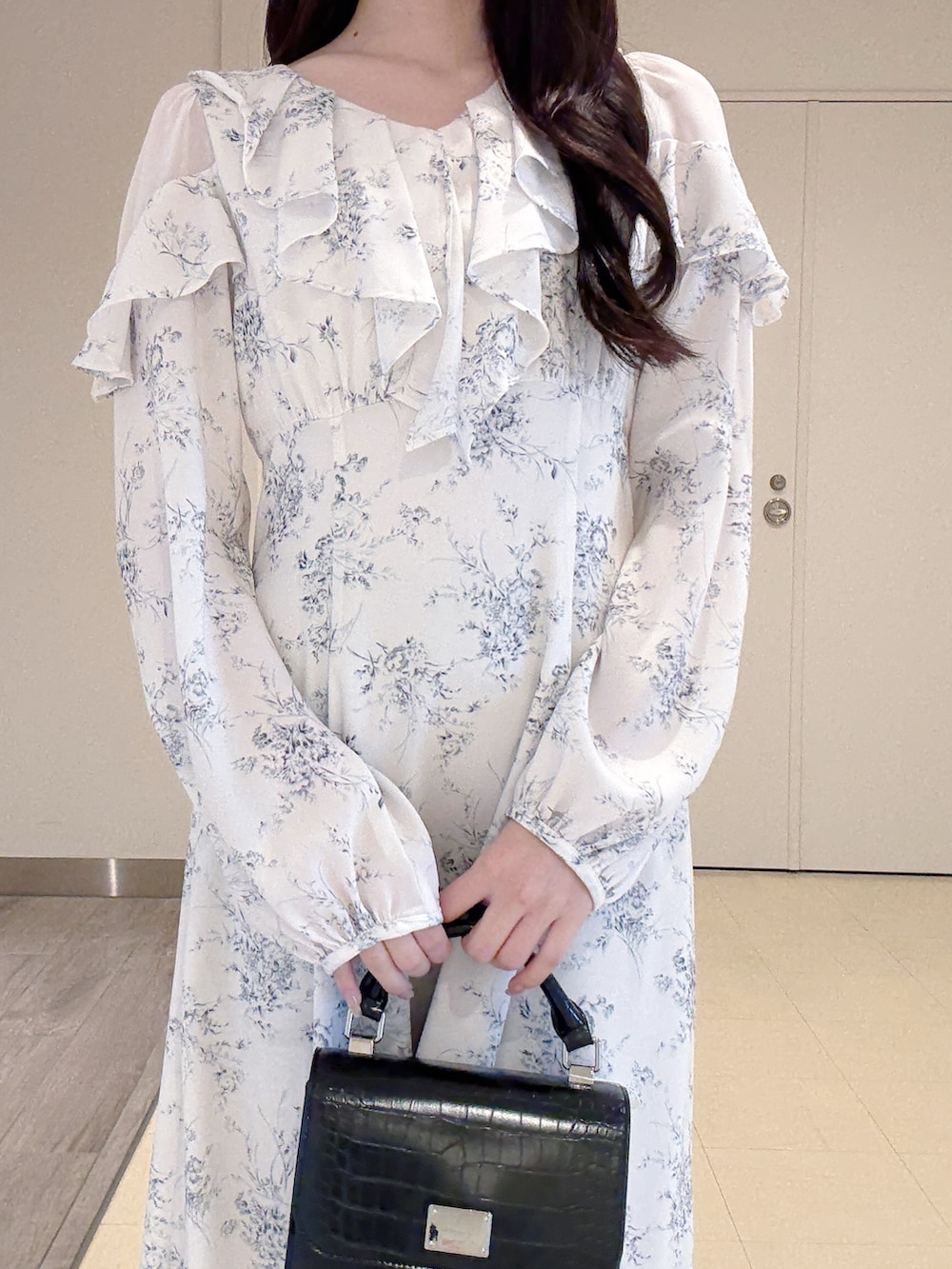 ホワイト系のワンピース、ブラック系のハンドバッグ、ホワイト系のブーツを着用したレディースの冬コーディネートの6枚目の写真