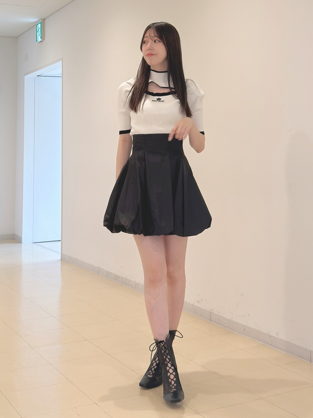 ホワイト系のニット/セーター、ブラック系のスカート、ブラック系のブーツを着用したレディースの春コーディネートの3枚目の写真