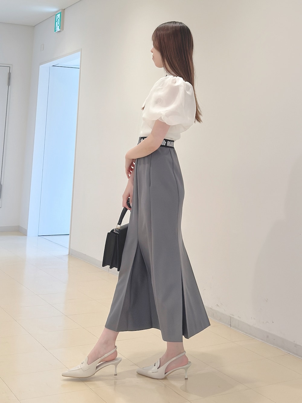 ホワイト系のニット/セーター、グレー系のスカート、ブラック系のハンドバッグを着用したレディースの春コーディネートの3枚目の写真