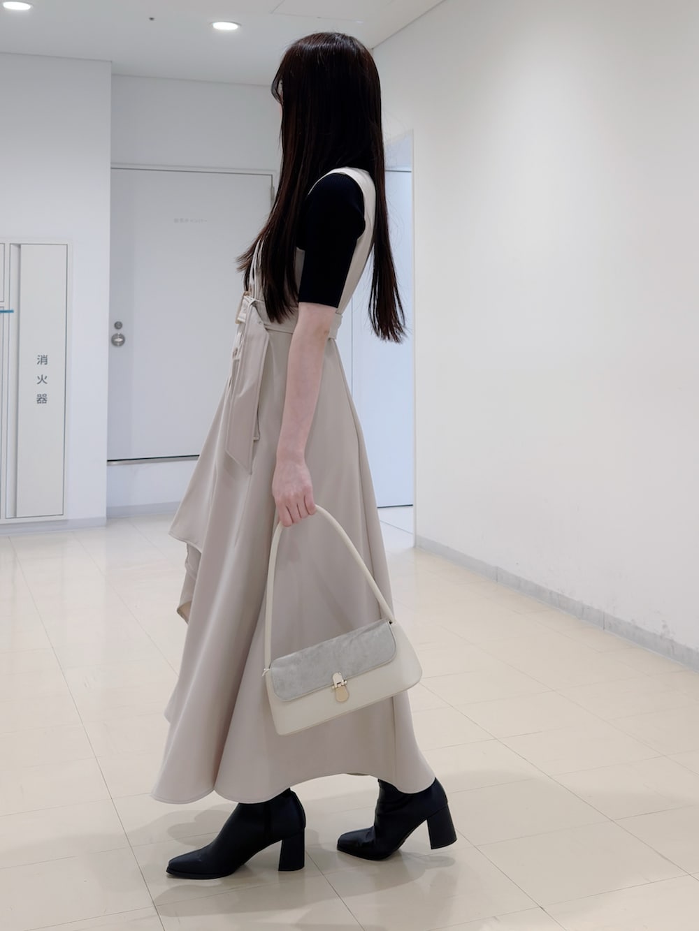 ブラック系のニット/セーター、ベージュ系のワンピース、ブラック系のブーツを着用したレディースの春コーディネートの3枚目の写真