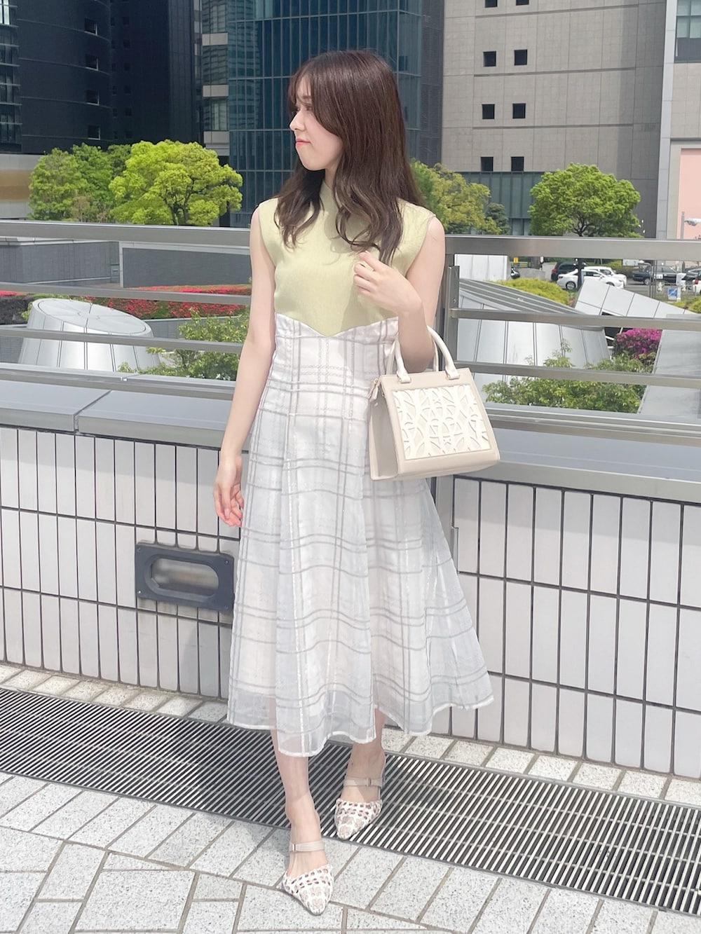 ベージュ系のショルダーバッグ、グリーン系のワンピース、その他のパンプスを着用したレディースの春コーディネートの3枚目の写真