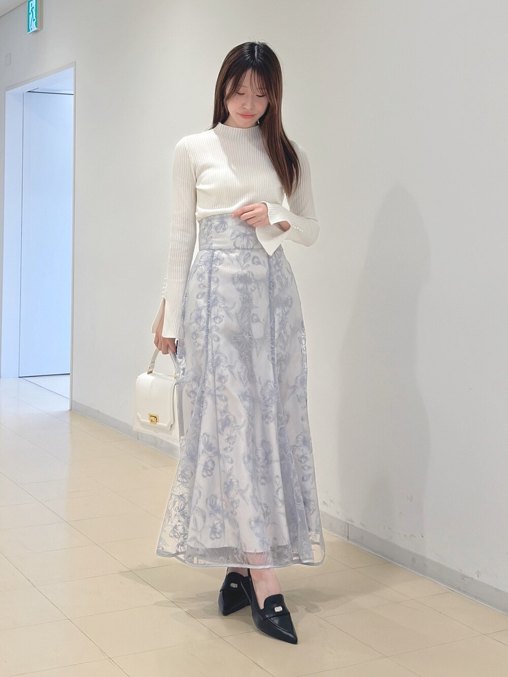 ホワイト系のニット/セーター、ブルー系のスカート、ホワイト系のハンドバッグを着用したレディースの冬コーディネートの4枚目の写真