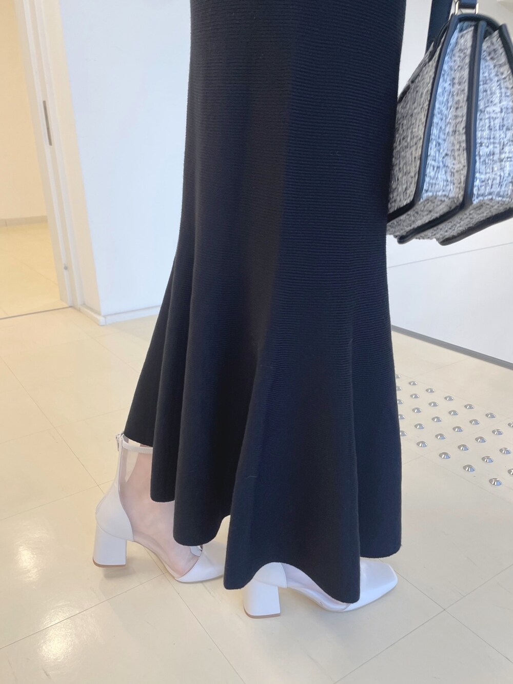 ホワイト系のブーツ、ブラック系のショルダーバッグ、ブラック系のワンピースを着用したレディースの秋コーディネートの7枚目の写真