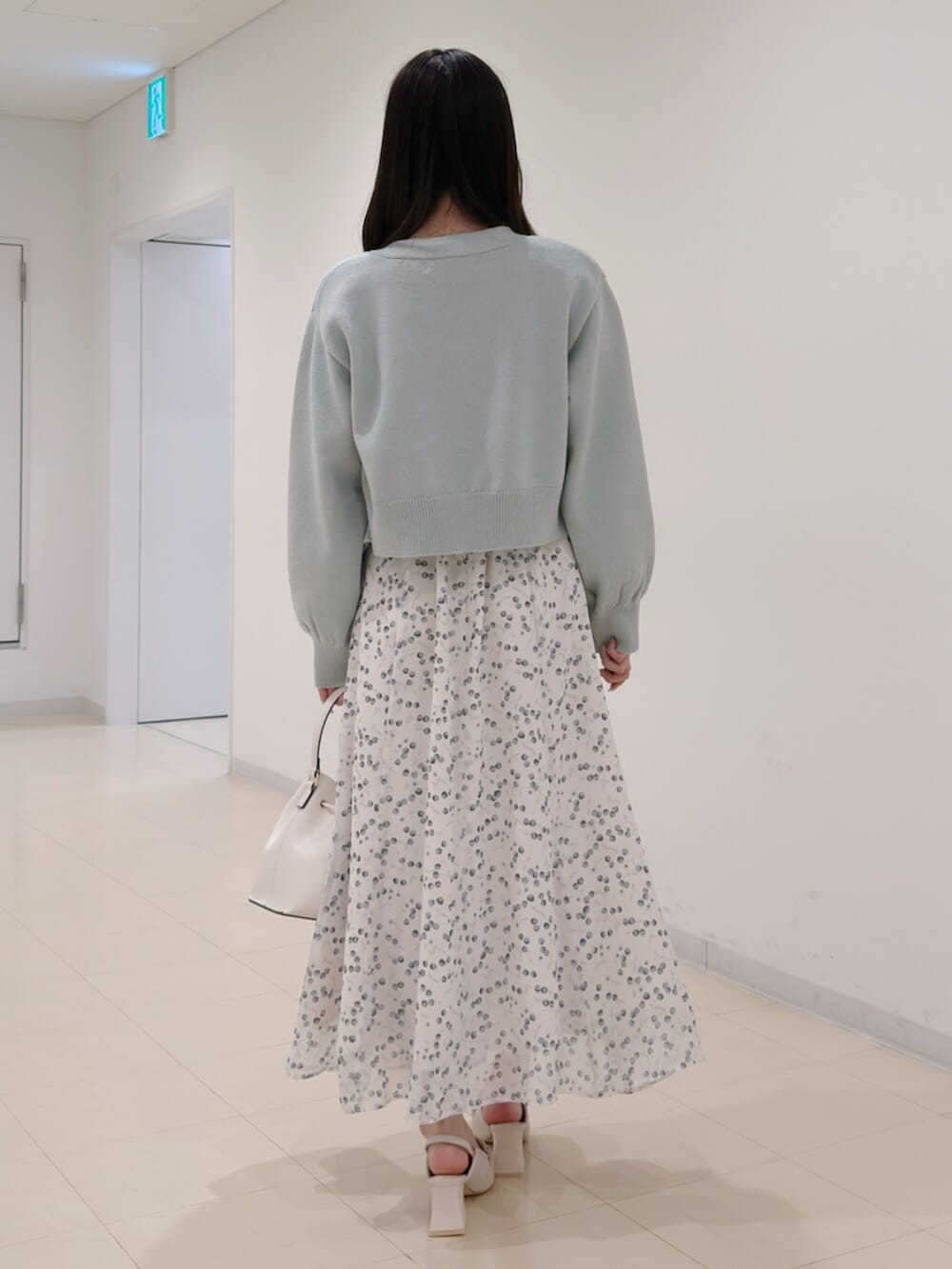 ホワイト系のショルダーバッグ、グリーン系のカーディガン/ボレロ、ホワイト系のワンピースを着用したレディースの冬コーディネートの4枚目の写真