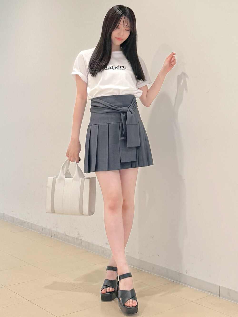 ホワイト系のTシャツ/カットソー、グレー系のスカート、ホワイト系のトートバッグを着用したレディースの春コーディネートの3枚目の写真