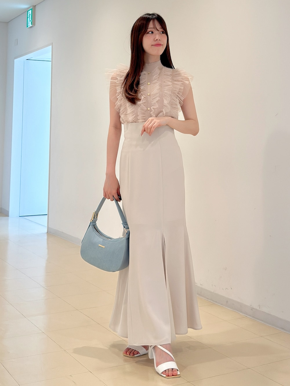 ピンク系のニット/セーター、ホワイト系のスカート、ブルー系のショルダーバッグを着用したレディースの春コーディネートの3枚目の写真