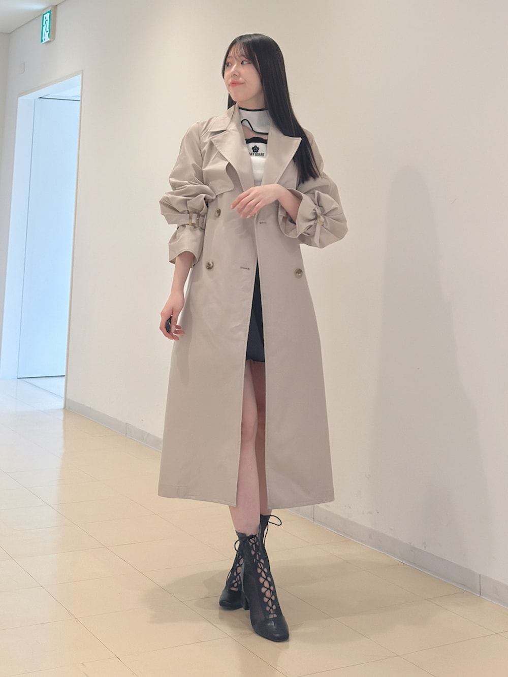 ベージュ系のトレンチコート、ホワイト系のニット/セーター、ブラック系のスカートを着用したレディースの春コーディネートの3枚目の写真