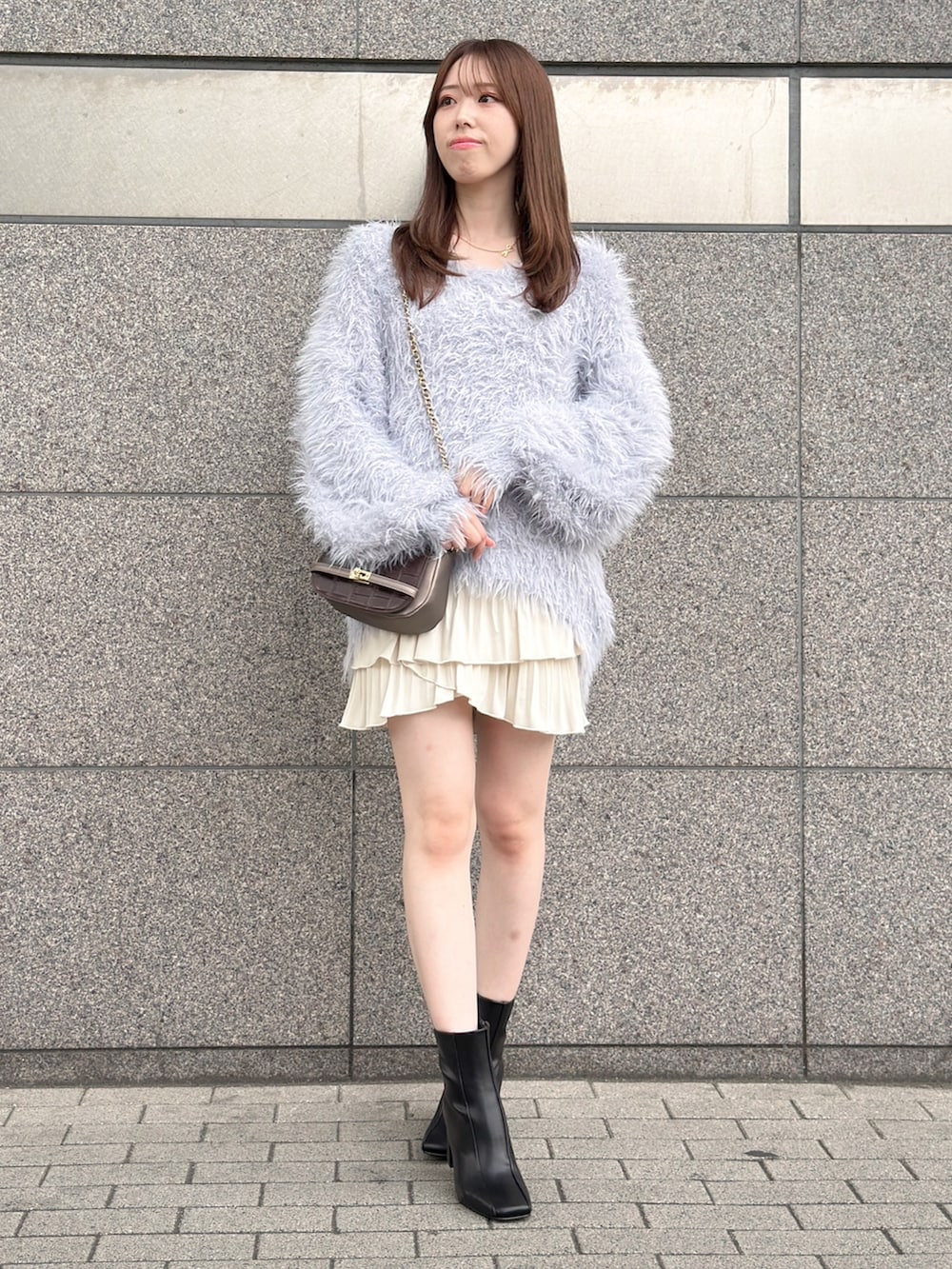 グレー系のニット/セーター、ホワイト系のスカート、ブラック系のブーツを着用したレディースの秋コーディネートの3枚目の写真