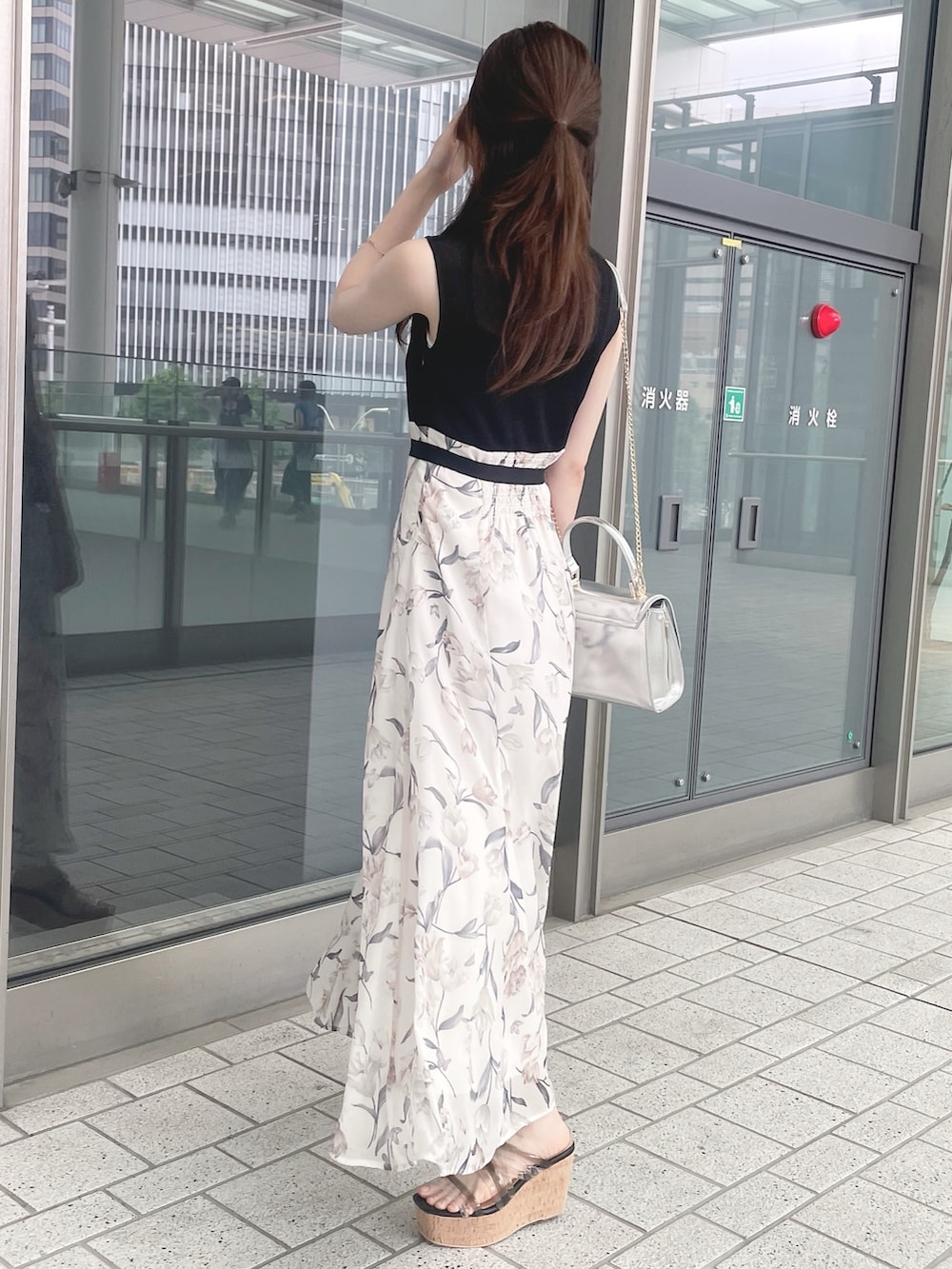 シルバー系のハンドバッグ、ブラック系のワンピース、ブラック系のサンダルを着用したレディースの春コーディネートの4枚目の写真