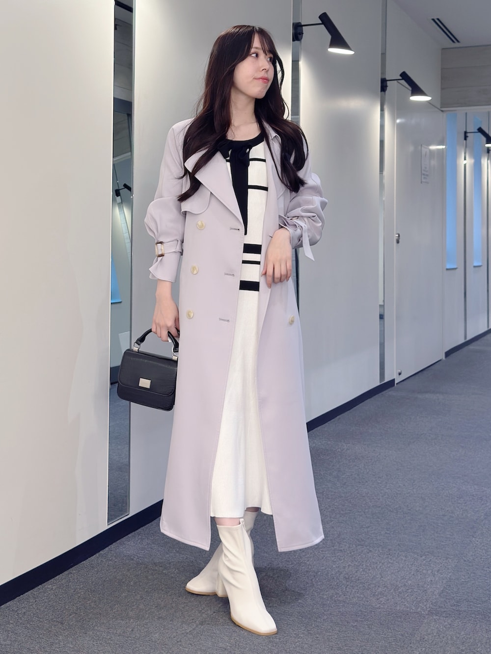 パープル系のトレンチコート、ホワイト系のワンピース、ブラック系のハンドバッグを着用したレディースの冬コーディネートの2枚目の写真
