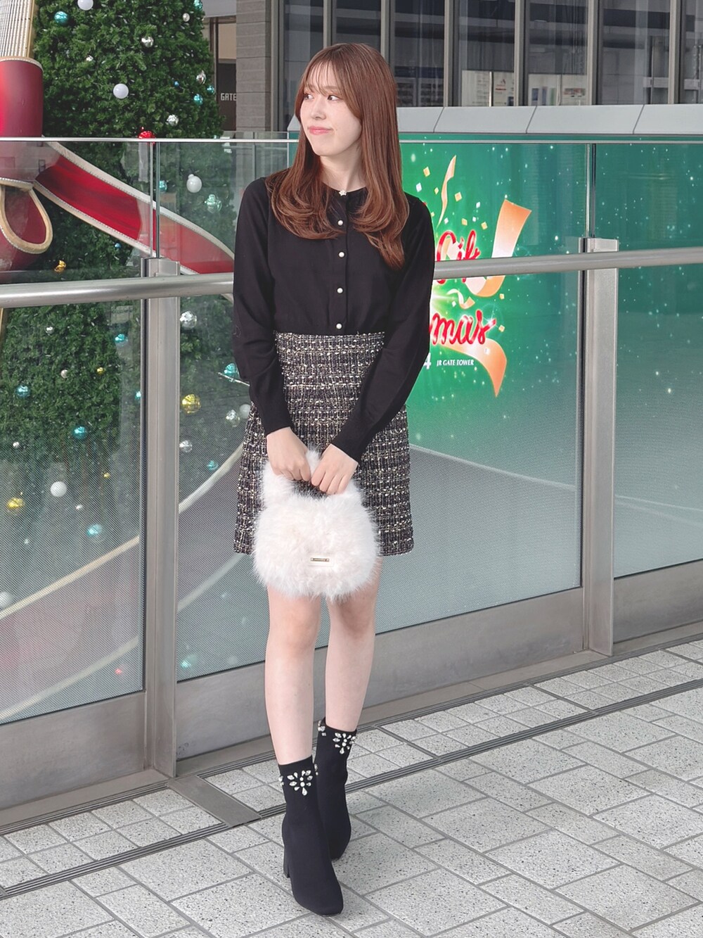 ブラック系のカーディガン/ボレロ、ブラック系のスカート、ホワイト系のハンドバッグを着用したレディースの秋コーディネートの2枚目の写真