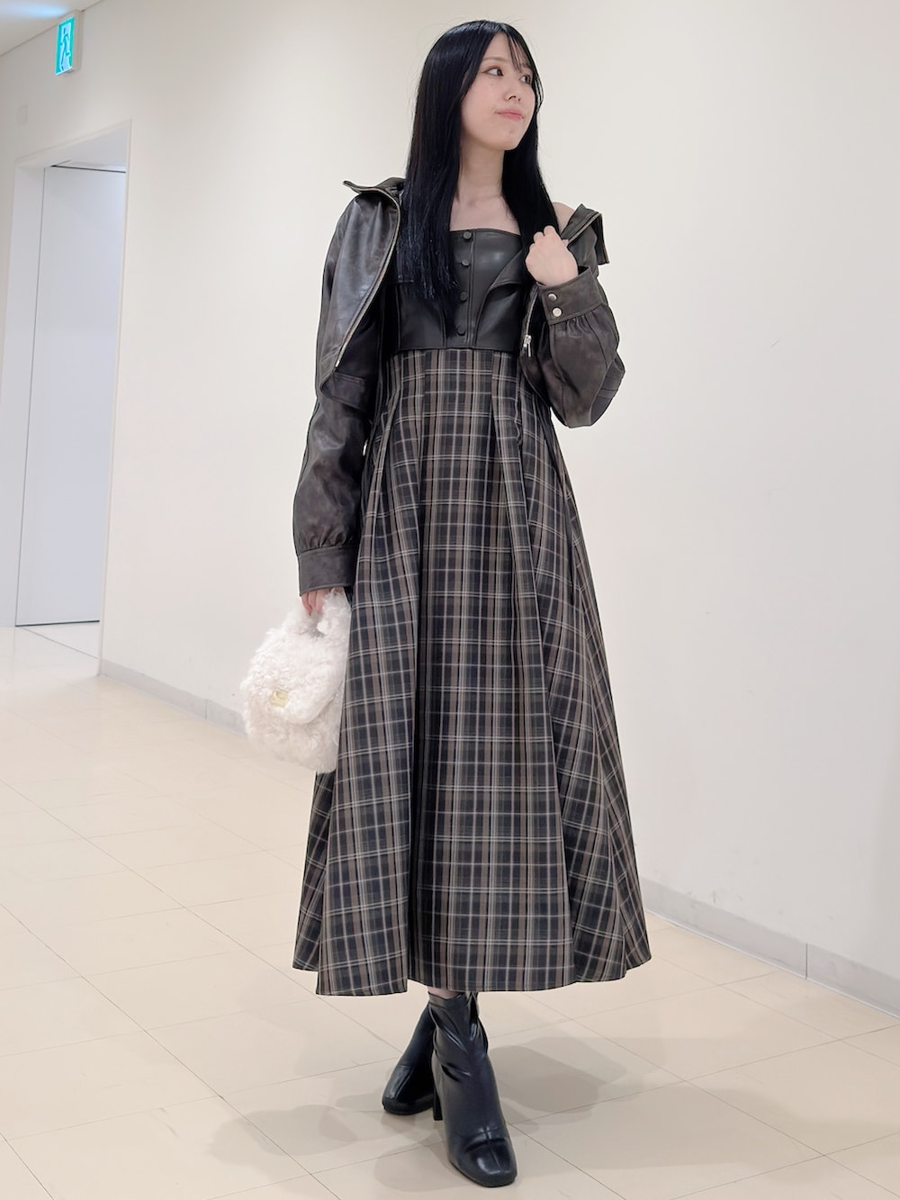 ブラウン系のブルゾン、ホワイト系のハンドバッグ、ブラウン系のワンピースを着用したレディースの秋コーディネートの3枚目の写真