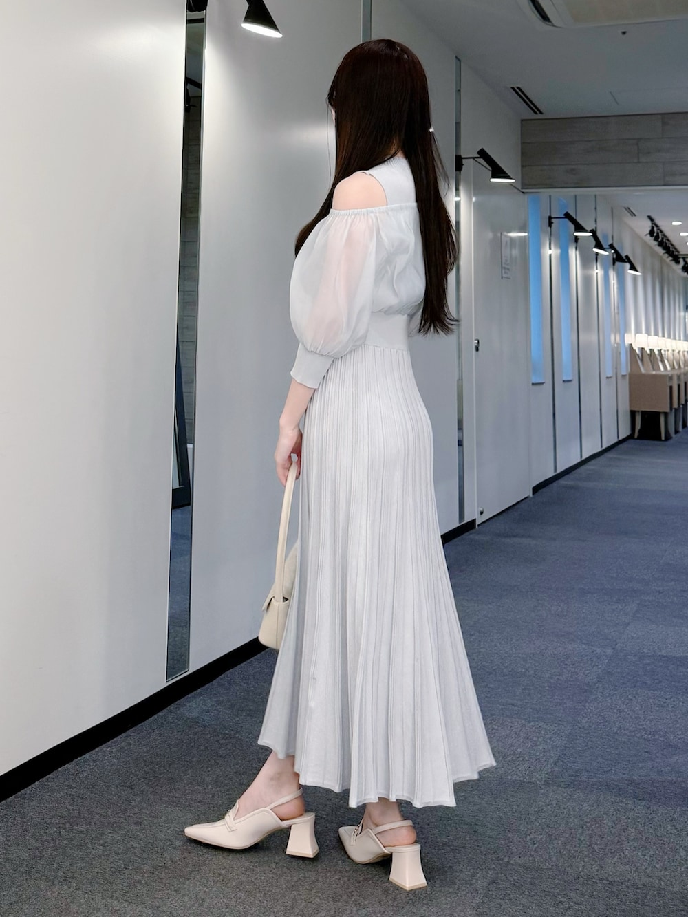 グレー系のワンピース、ホワイト系のハンドバッグ、ホワイト系のパンプスを着用したレディースの春コーディネートの3枚目の写真