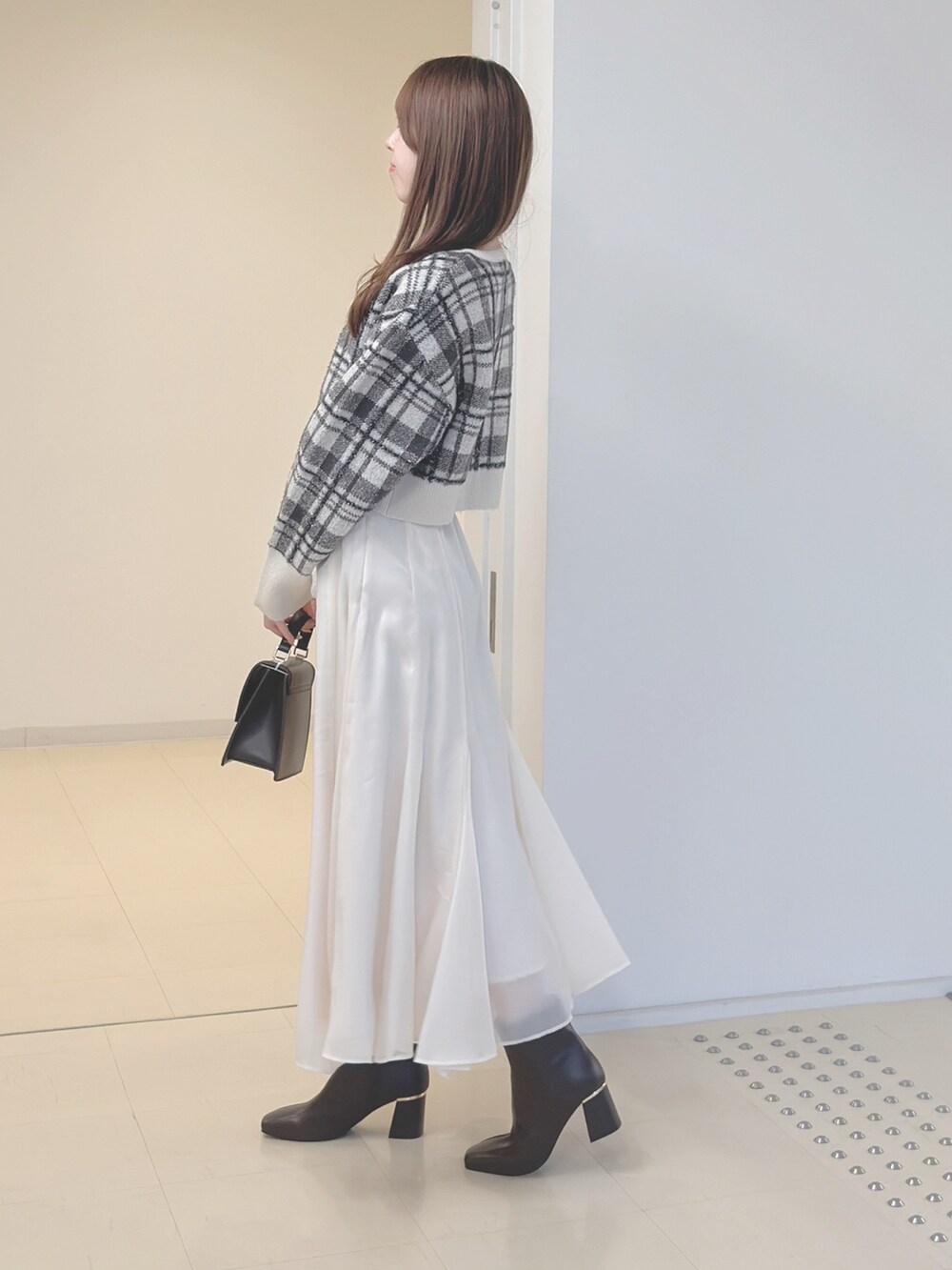 ホワイト系のカーディガン/ボレロ、ブラウン系のハンドバッグ、ホワイト系のスカートを着用したレディースの秋コーディネートの4枚目の写真