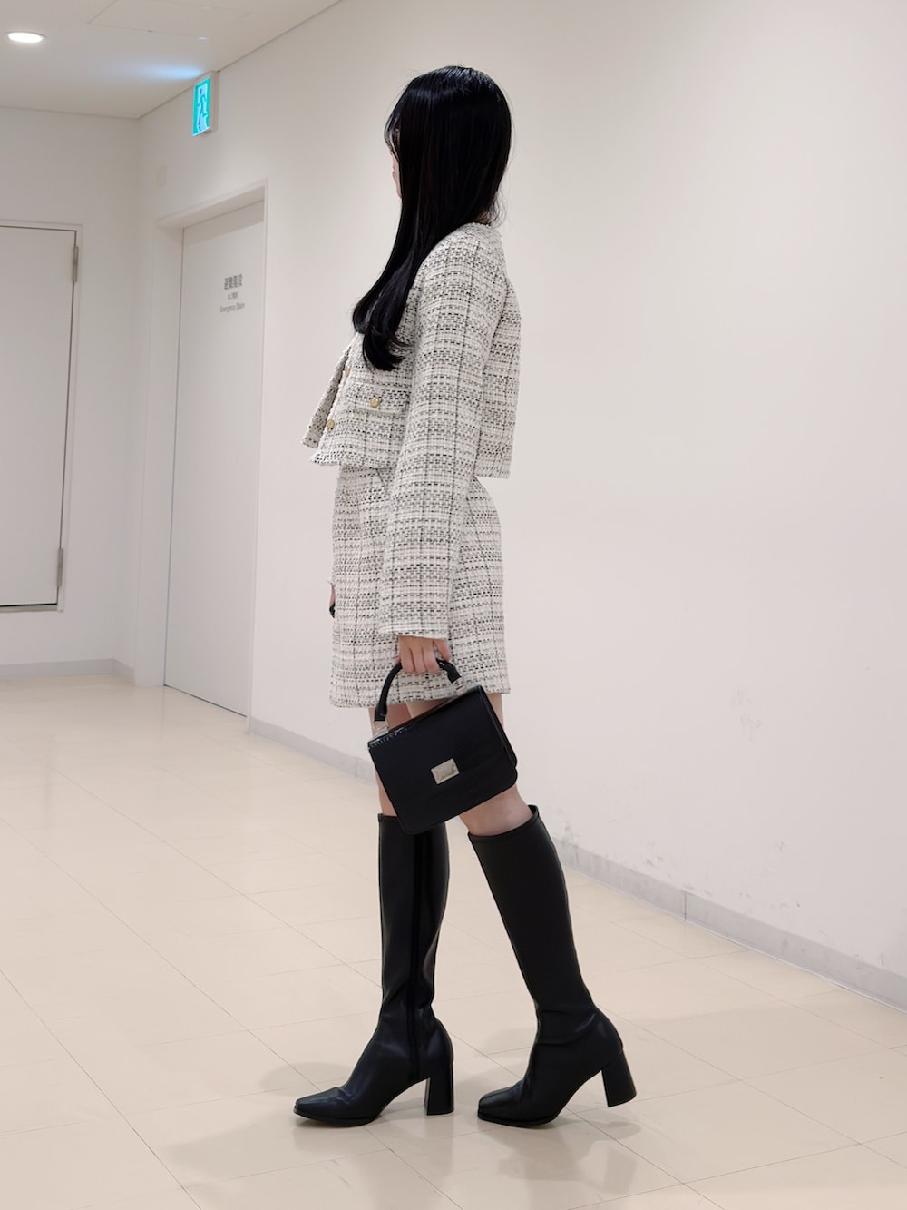 ホワイト系のノーカラージャケット、ベージュ系のニット/セーター、ホワイト系のスカートを着用したレディースの秋コーディネートの3枚目の写真