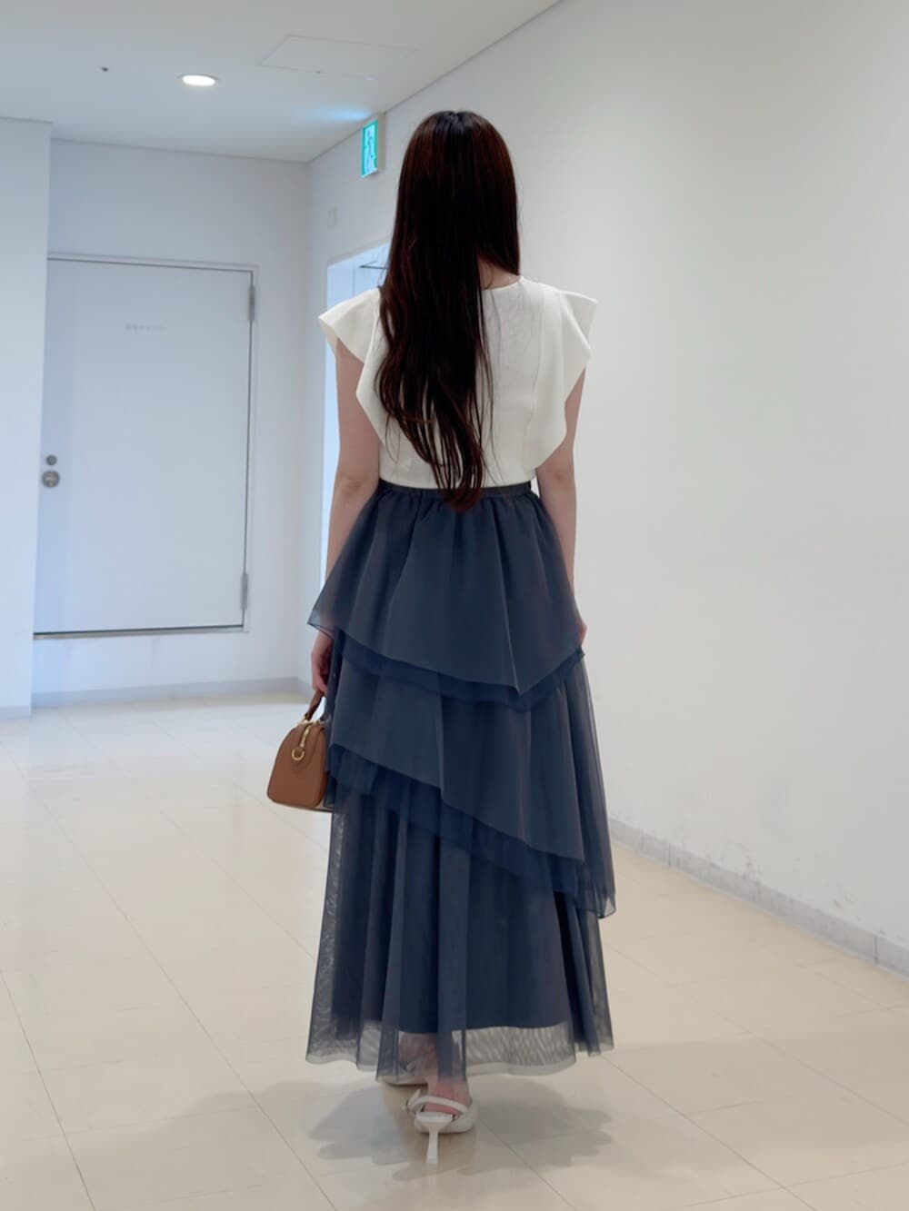 ブラウン系のハンドバッグ、ホワイト系のパンプス、ホワイト系のニット/セーターを着用したレディースの夏コーディネートの4枚目の写真