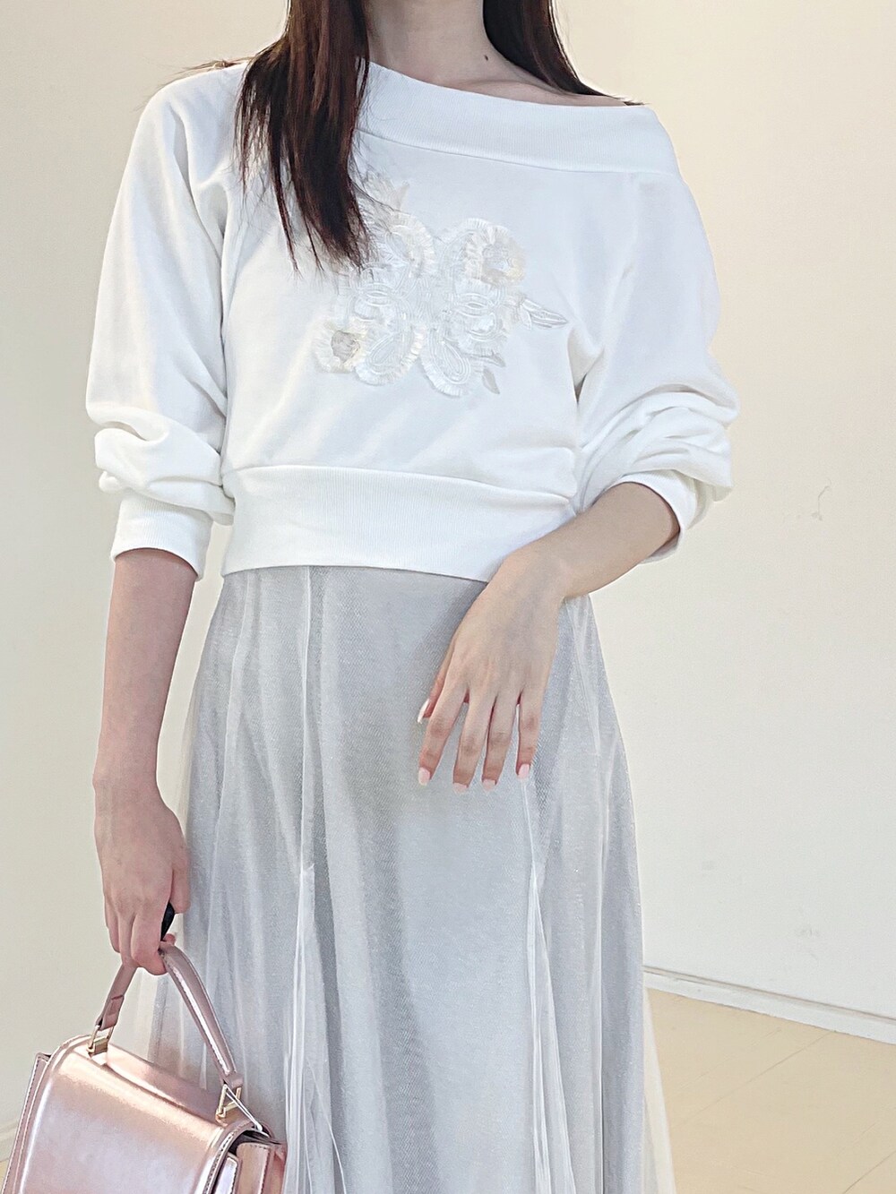 ホワイト系のスウェット、ホワイト系のスカート、ピンク系のハンドバッグを着用したレディースの秋コーディネートの6枚目の写真