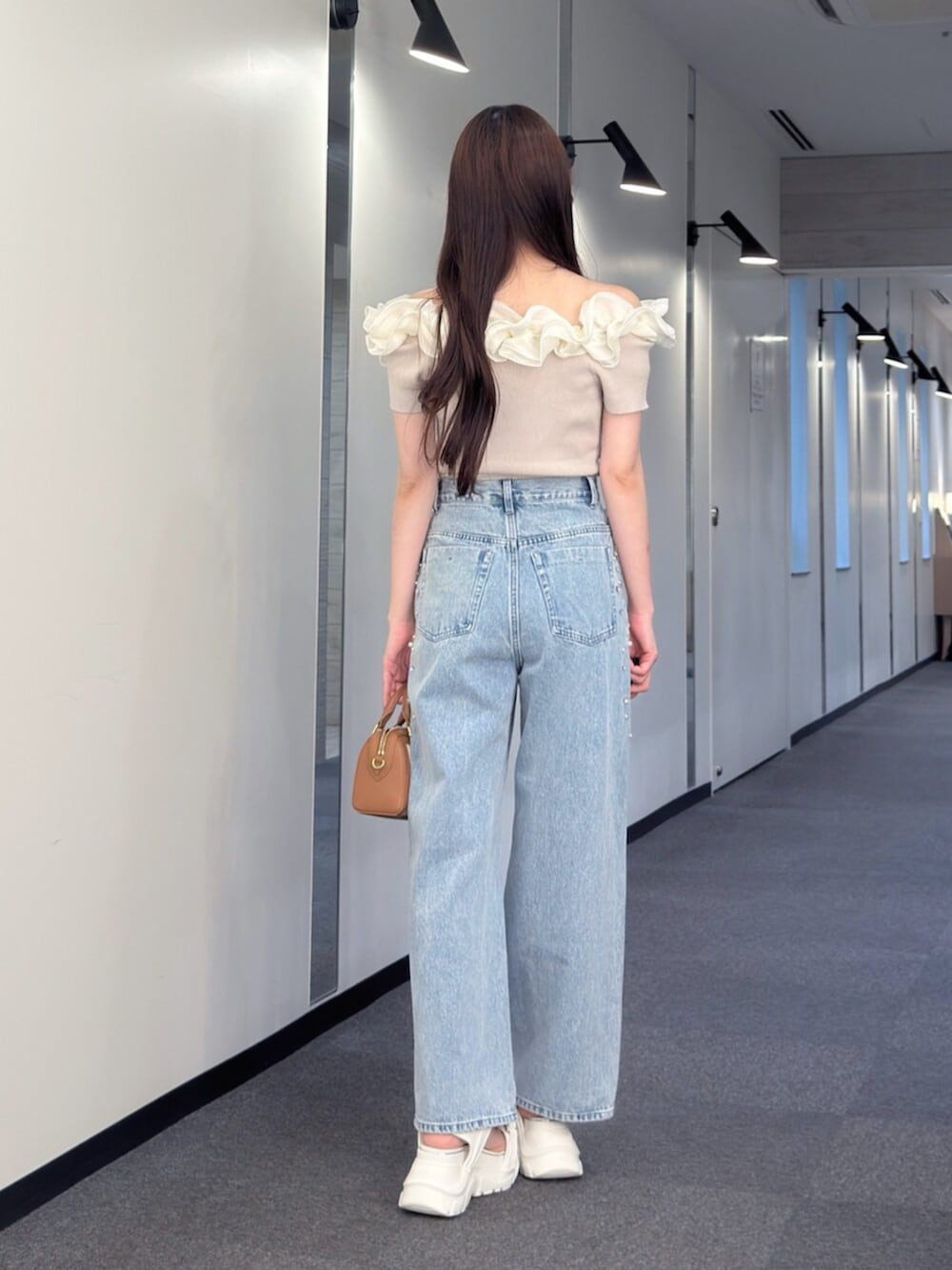 ブラウン系のハンドバッグ、ブルー系のデニムパンツ、ホワイト系のサンダルを着用したレディースの夏コーディネートの4枚目の写真