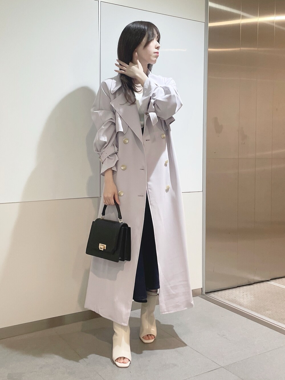 ブラック系のハンドバッグ、パープル系のトレンチコート、ホワイト系のニット/セーターを着用したレディースの冬コーディネートの3枚目の写真