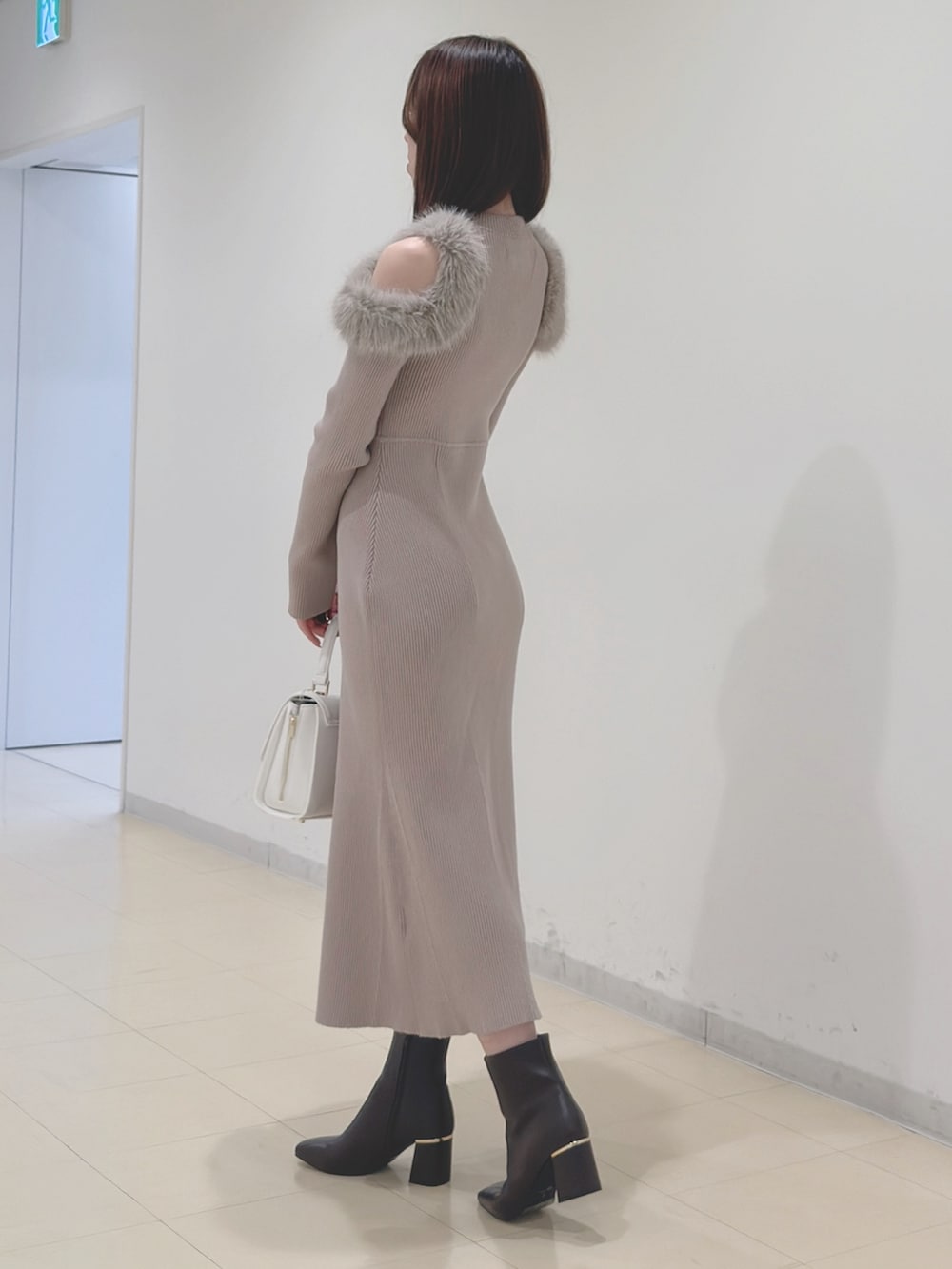 ベージュ系のワンピース、ホワイト系のハンドバッグ、ブラウン系のブーツを着用したレディースの冬コーディネートの6枚目の写真