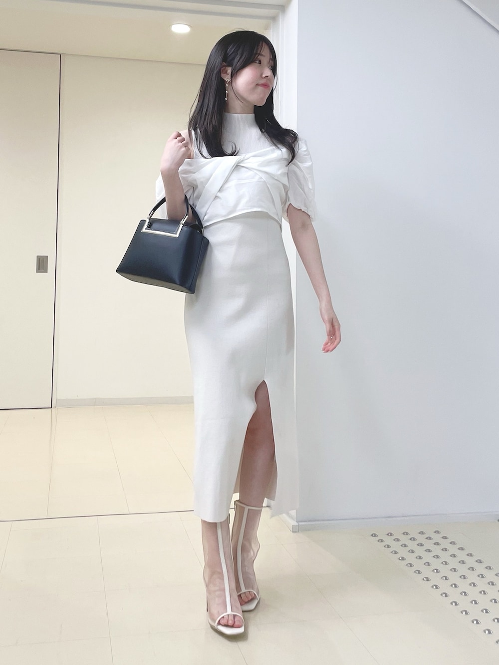 ホワイト系のワンピース、ブラック系のハンドバッグ、ホワイト系のブーツを着用したレディースの春コーディネートの2枚目の写真