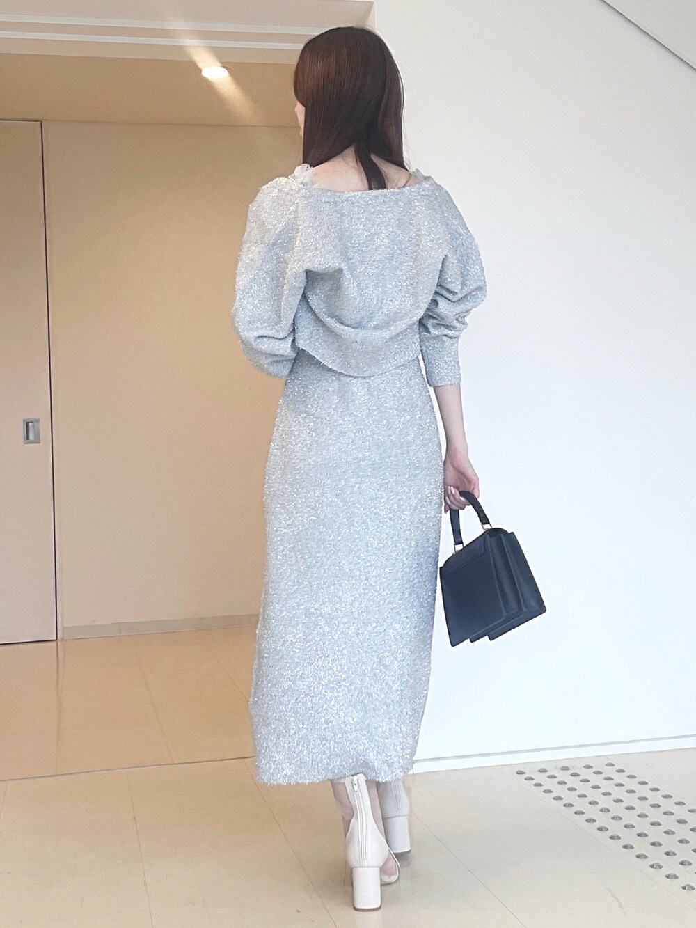 ホワイト系のブーツ、ブラック系のハンドバッグ、シルバー系のワンピースを着用したレディースの秋コーディネートの6枚目の写真