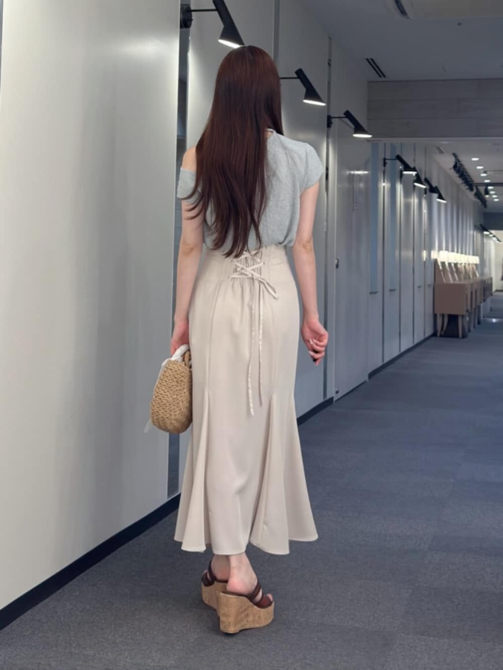 ホワイト系のスカート、ベージュ系のハンドバッグ、ブラウン系のサンダルを着用したレディースの夏コーディネートの3枚目の写真
