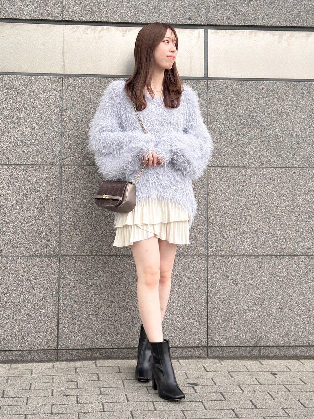 グレー系のニット/セーター、ホワイト系のスカート、ブラック系のブーツを着用したレディースの秋コーディネートの4枚目の写真