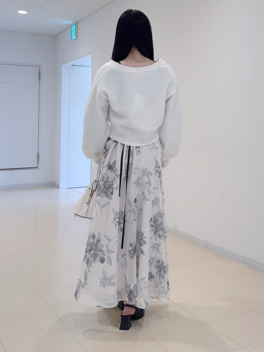 ホワイト系のカーディガン/ボレロ、ホワイト系のスカート、ホワイト系のショルダーバッグを着用したレディースの冬コーディネートの5枚目の写真