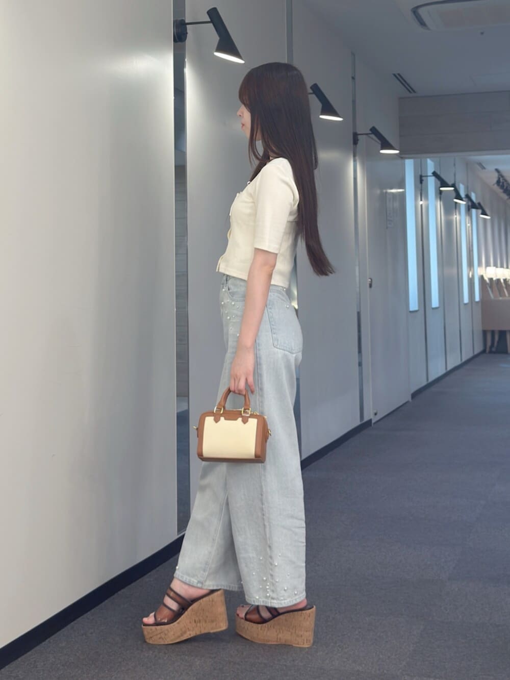 ブラウン系のハンドバッグ、ブラウン系のサンダル、ブルー系のデニムパンツを着用したレディースの夏コーディネートの4枚目の写真