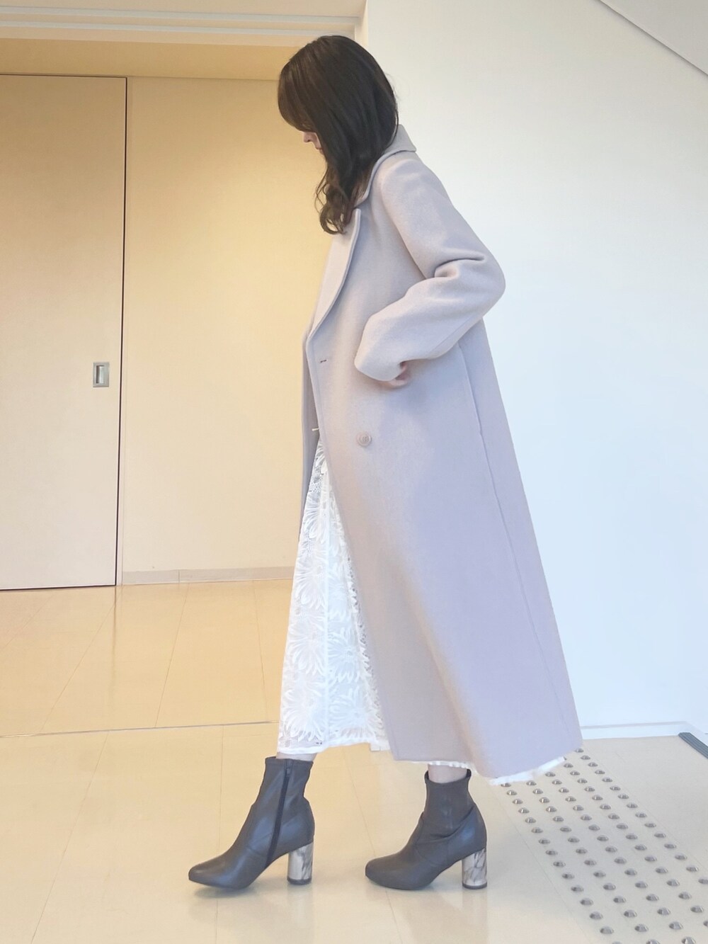 グレー系のニット/セーター、ホワイト系のスカート、ベージュ系のチェスターコートを着用したレディースの秋コーディネートの5枚目の写真