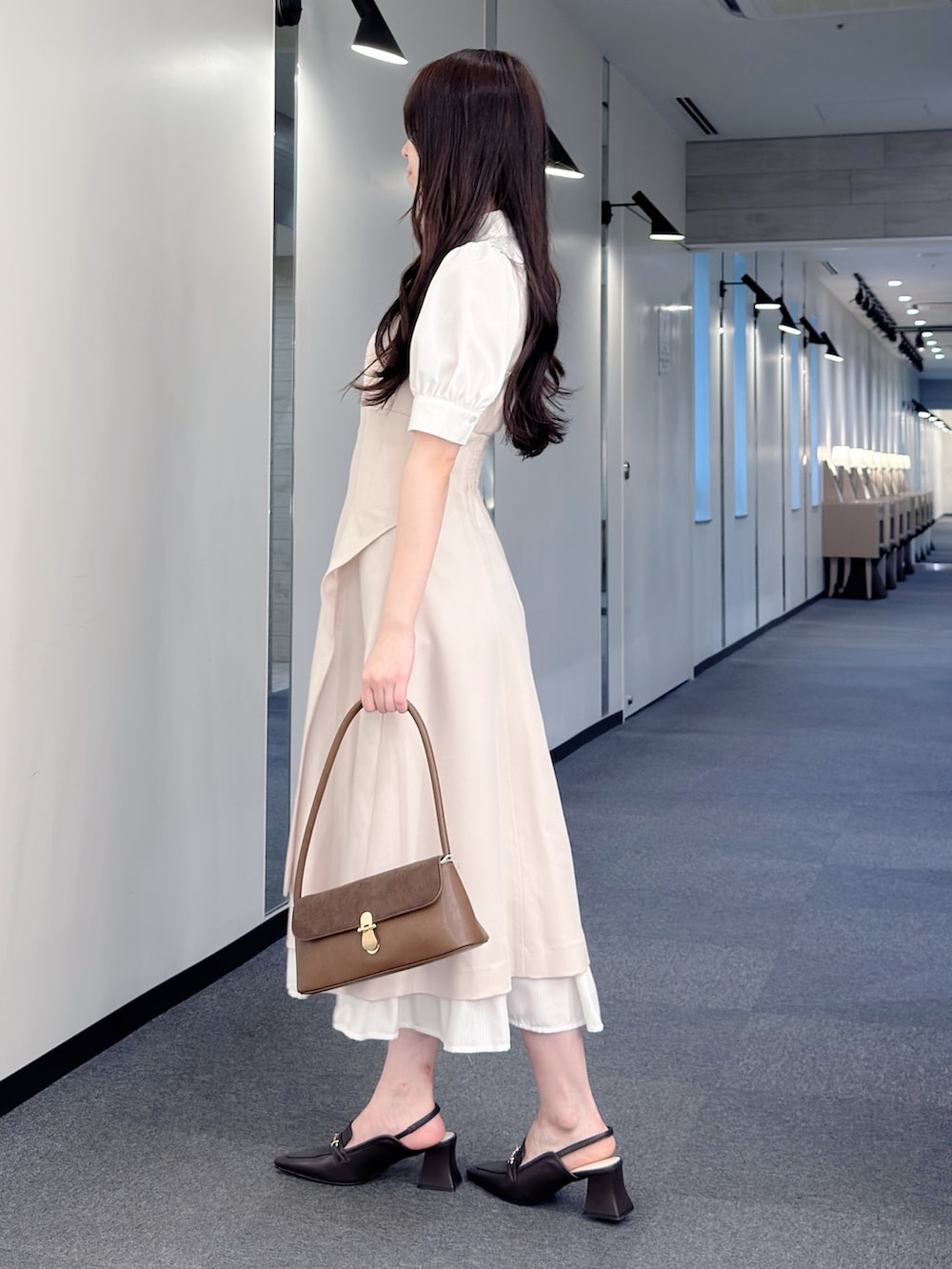 ベージュ系のワンピース、ブラウン系のハンドバッグ、ブラウン系のパンプスを着用したレディースの春コーディネートの3枚目の写真