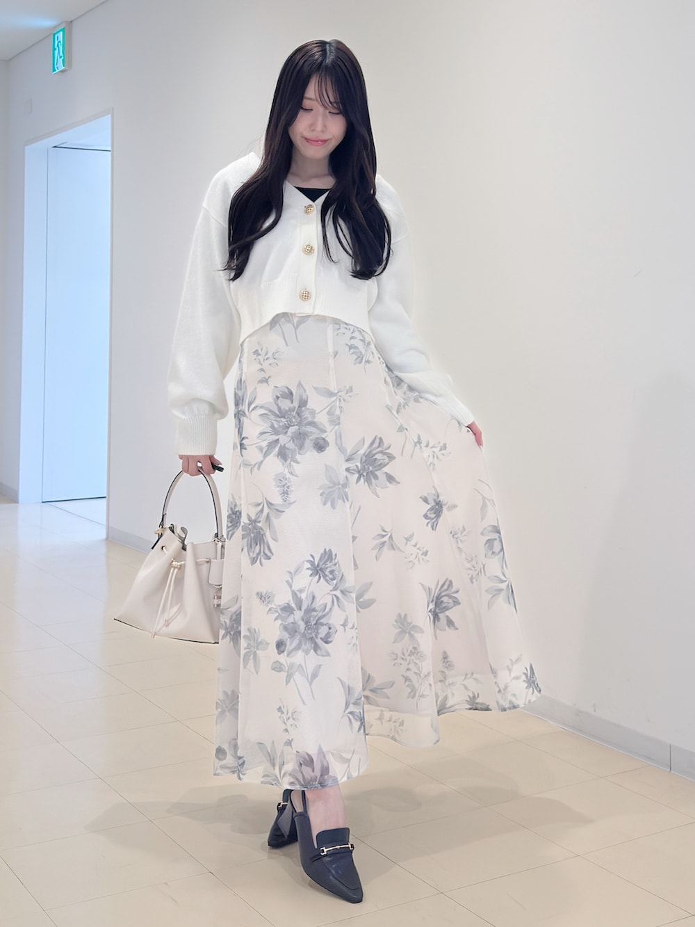 ホワイト系のカーディガン/ボレロ、ホワイト系のスカート、ホワイト系のショルダーバッグを着用したレディースの冬コーディネートの3枚目の写真