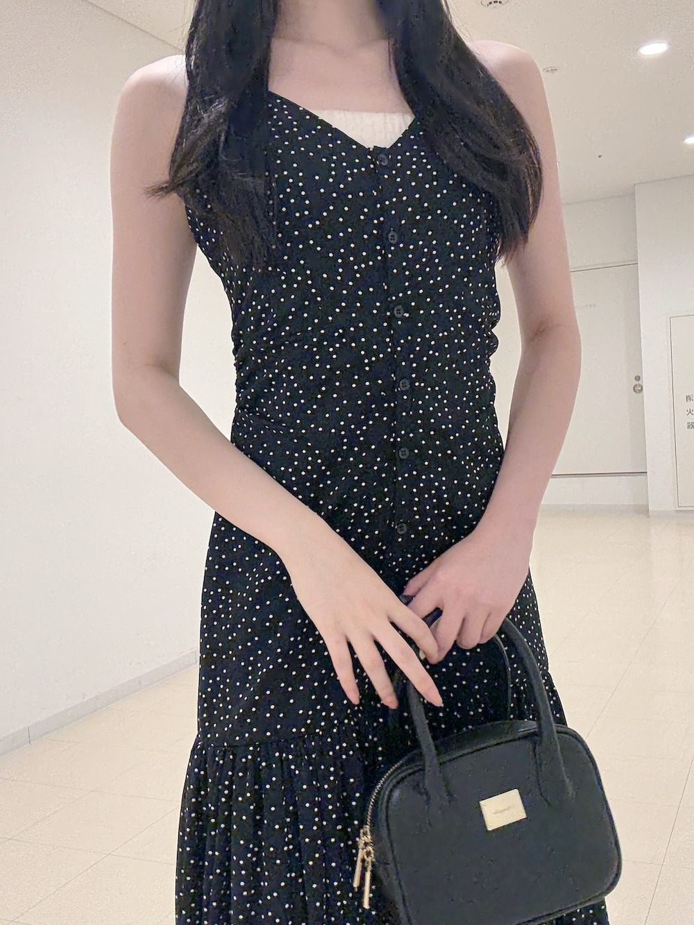 ブラック系のワンピース、ブラック系のハンドバッグ、ホワイト系のパンプスを着用したレディースの秋コーディネートの6枚目の写真