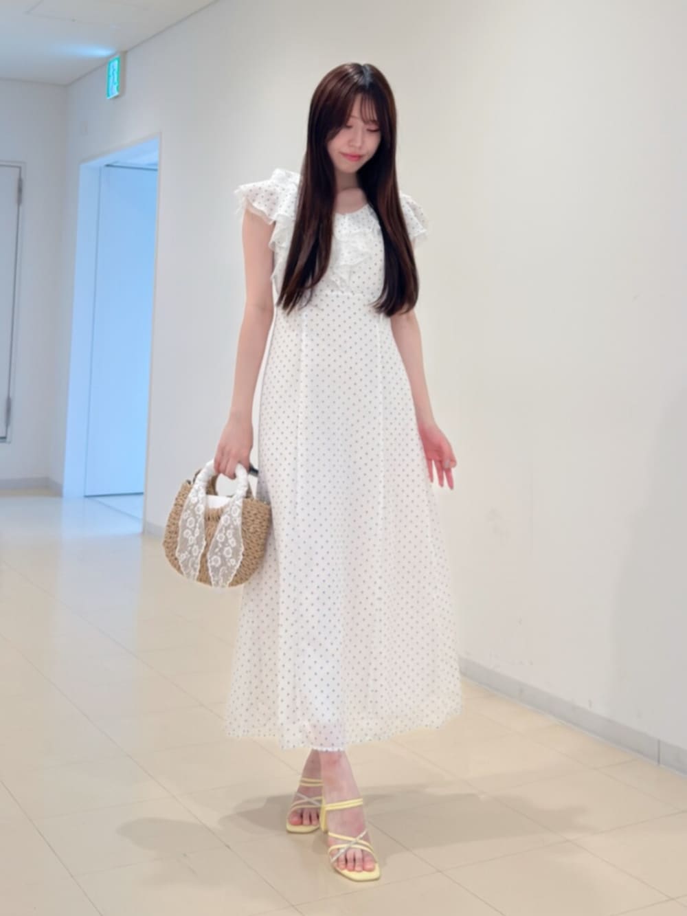ベージュ系のハンドバッグ、ホワイト系のワンピース、イエロー系のサンダルを着用したレディースの夏コーディネートの2枚目の写真