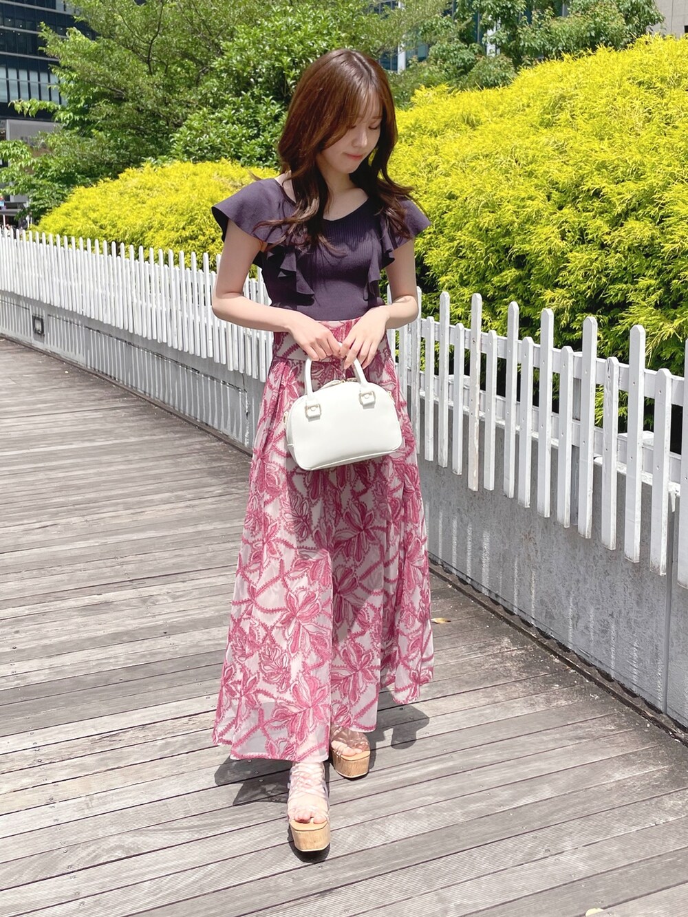 レッド系のスカート、グレー系のニット/セーター、ホワイト系のボストンバッグを着用したレディースの春コーディネートの3枚目の写真