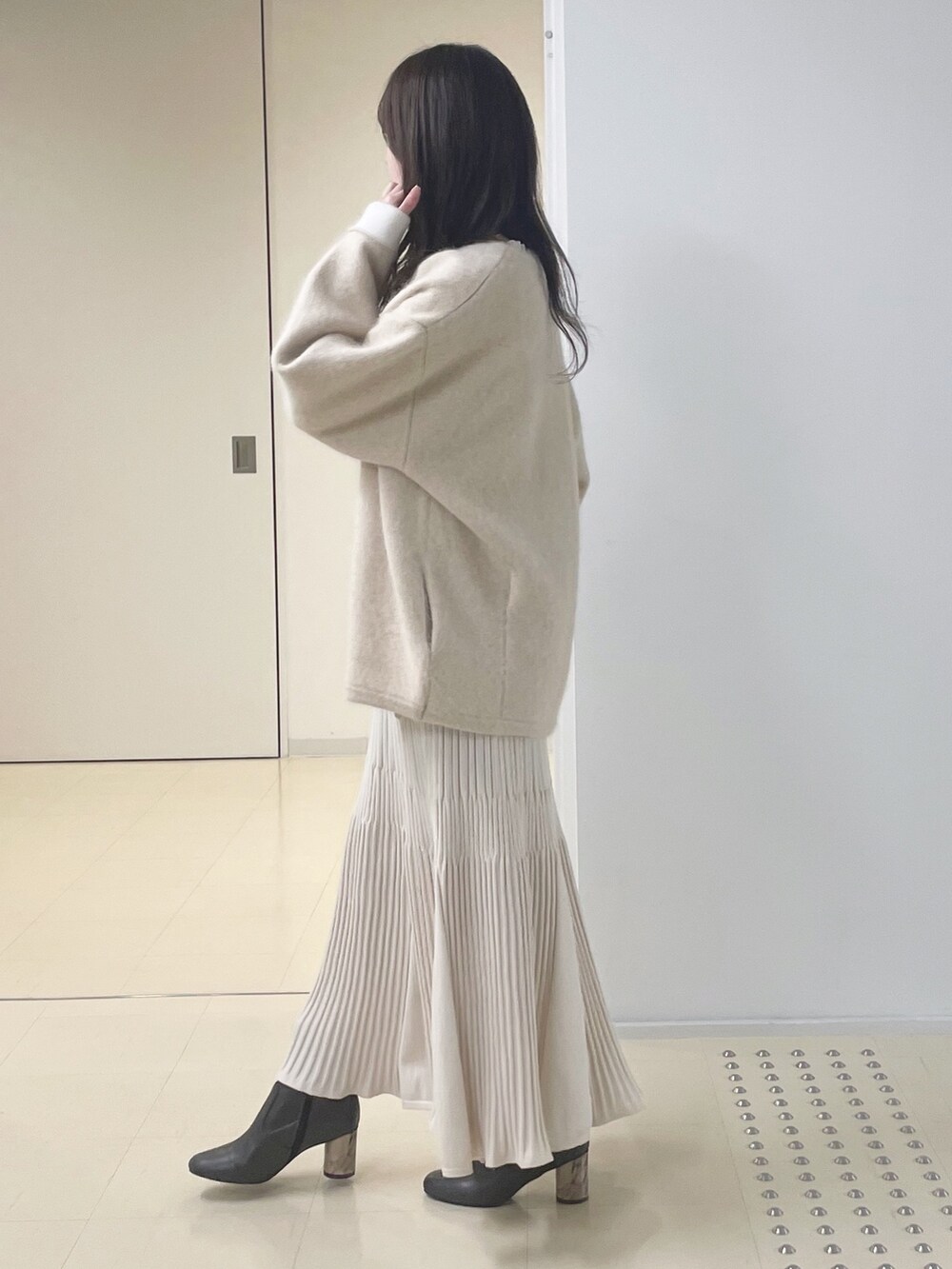 ベージュ系のカーディガン/ボレロ、ブラウン系のブーツ、ホワイト系のワンピースを着用したレディースの冬コーディネートの3枚目の写真