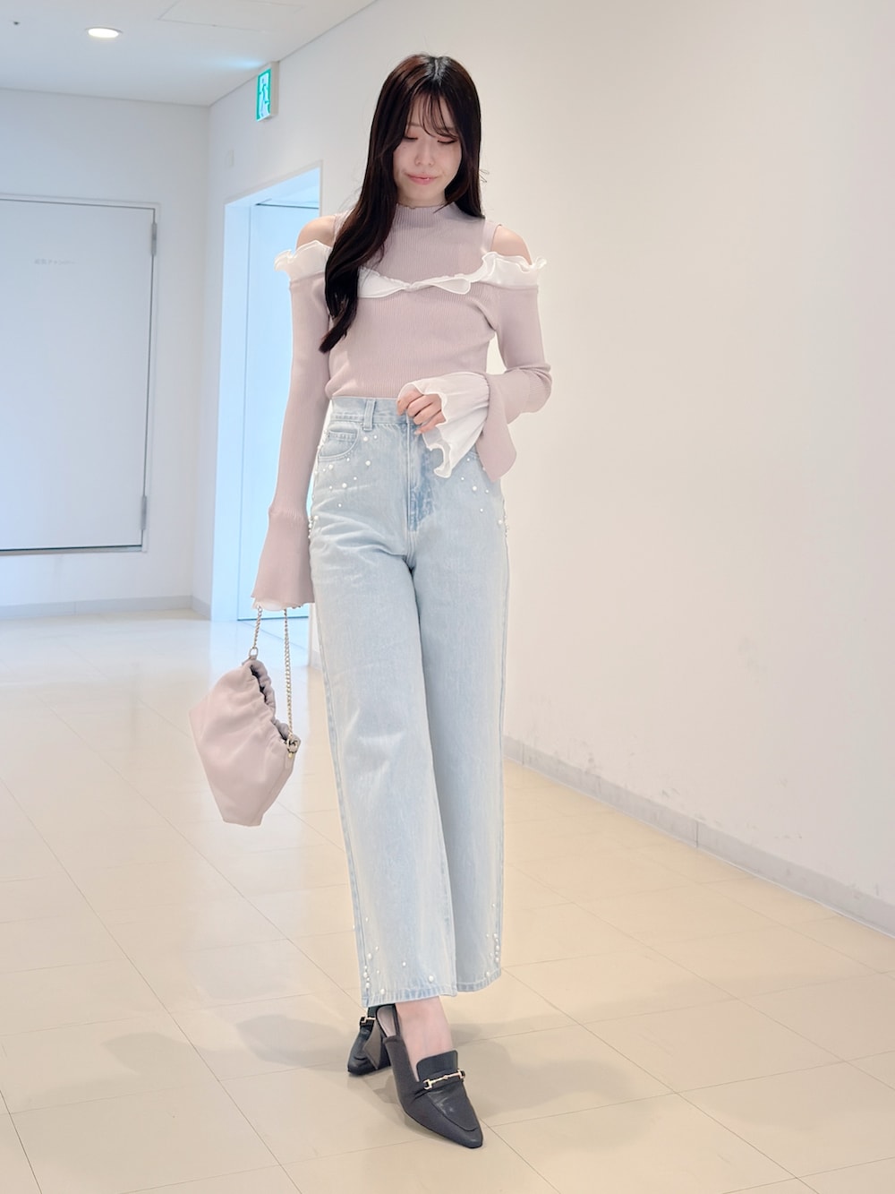 ベージュ系のニット/セーター、ブルー系のデニムパンツ、ピンク系のショルダーバッグを着用したレディースの春コーディネートの2枚目の写真