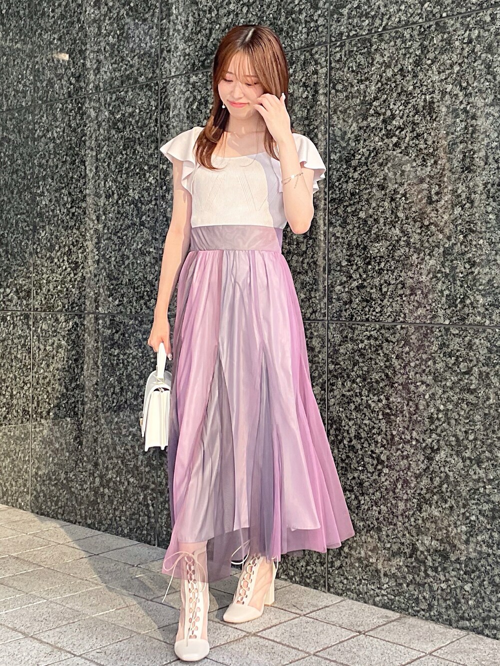 ピンク系のニット/セーター、ホワイト系のハンドバッグ、ホワイト系のブーツを着用したレディースの夏コーディネートの2枚目の写真