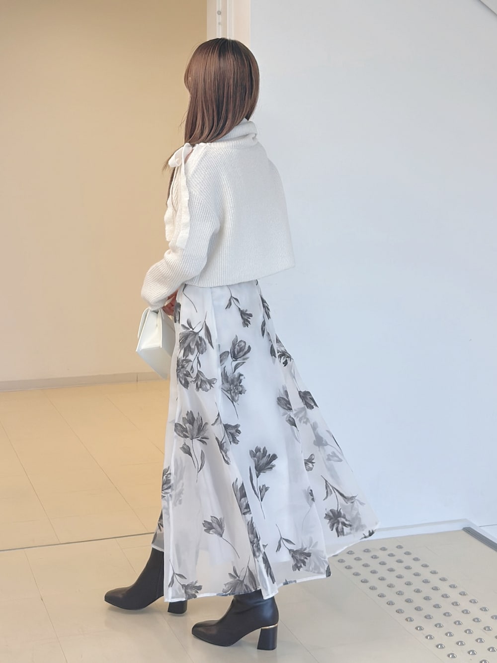 ホワイト系のニット/セーター、ホワイト系のスカート、ホワイト系のショルダーバッグを着用したレディースの秋コーディネートの4枚目の写真