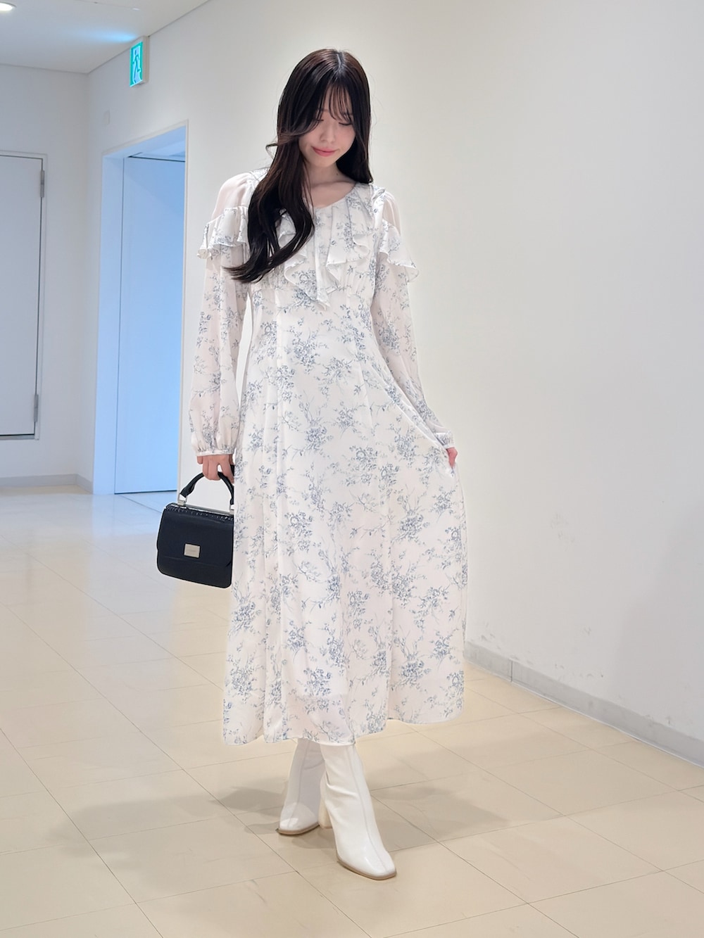 ホワイト系のワンピース、ブラック系のハンドバッグ、ホワイト系のブーツを着用したレディースの冬コーディネートの2枚目の写真