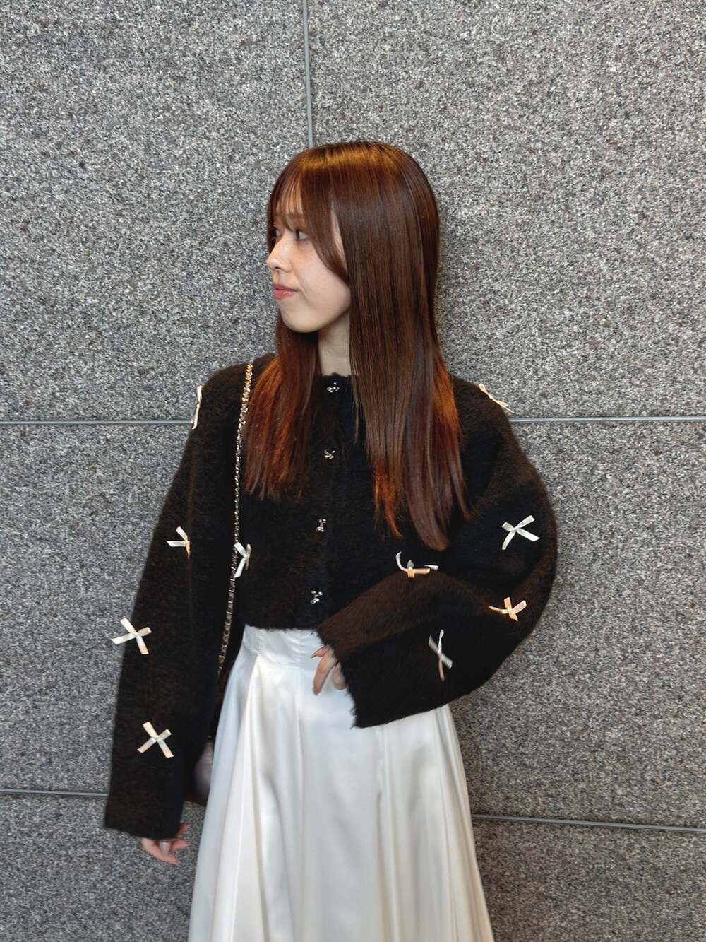 ブラック系のカーディガン/ボレロ、ホワイト系のスカート、ブラウン系のハンドバッグを着用したレディースの秋コーディネートの6枚目の写真