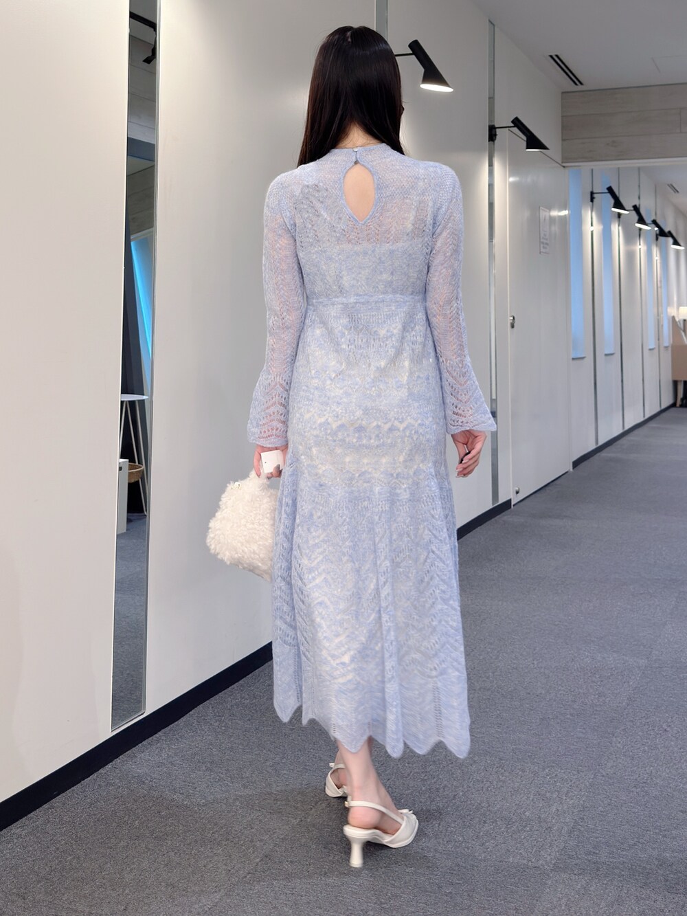 ブルー系のワンピース、ホワイト系のハンドバッグ、ホワイト系のパンプスを着用したレディースの秋コーディネートの4枚目の写真