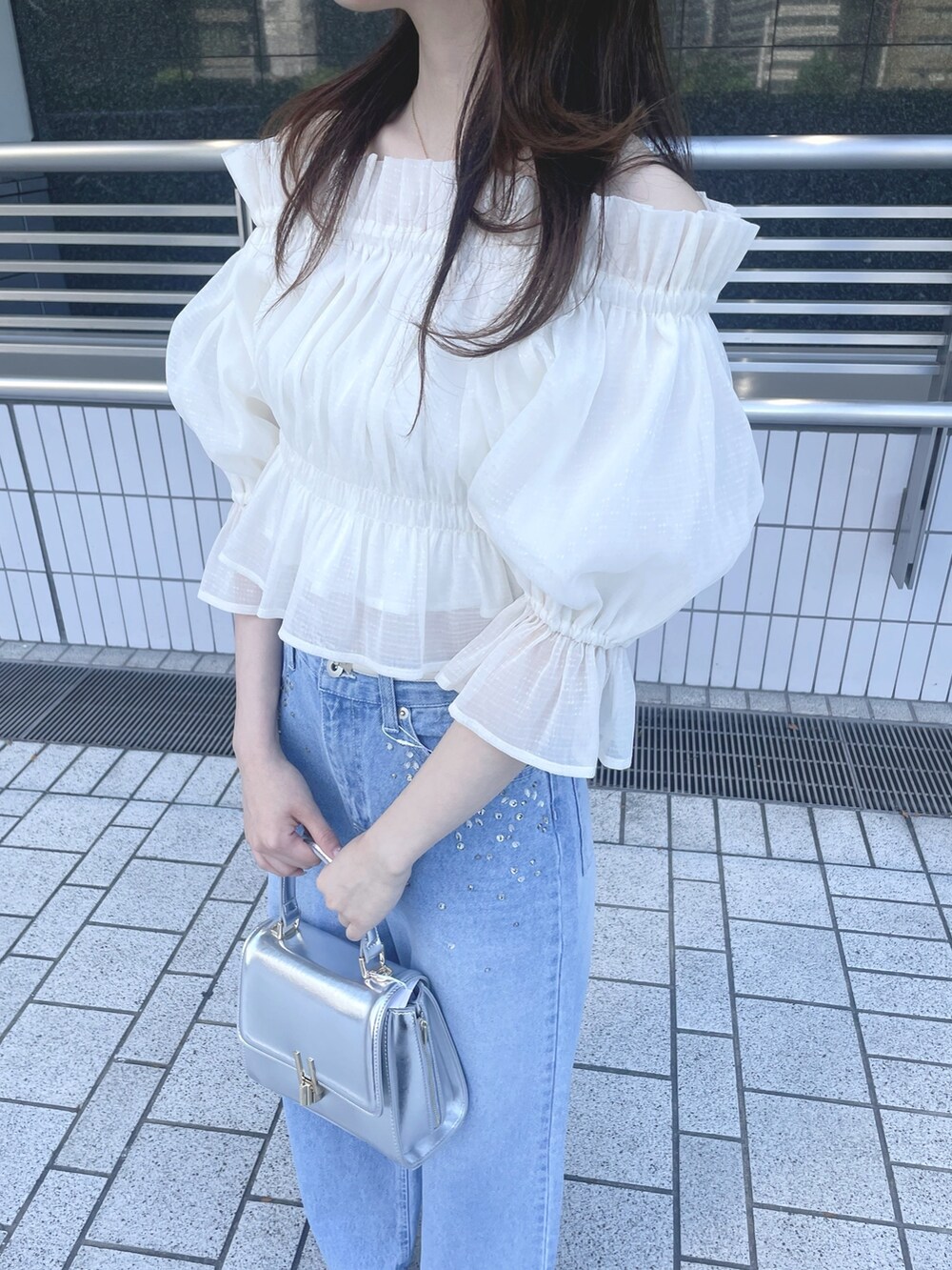 ブルー系のデニムパンツ、シルバー系のハンドバッグ、シルバー系のサンダルを着用したレディースの春コーディネートの6枚目の写真