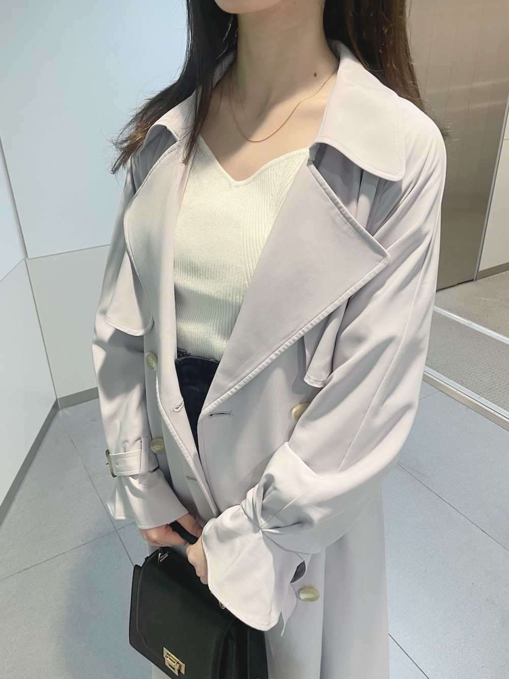 ブラック系のハンドバッグ、パープル系のトレンチコート、ホワイト系のニット/セーターを着用したレディースの冬コーディネートの6枚目の写真