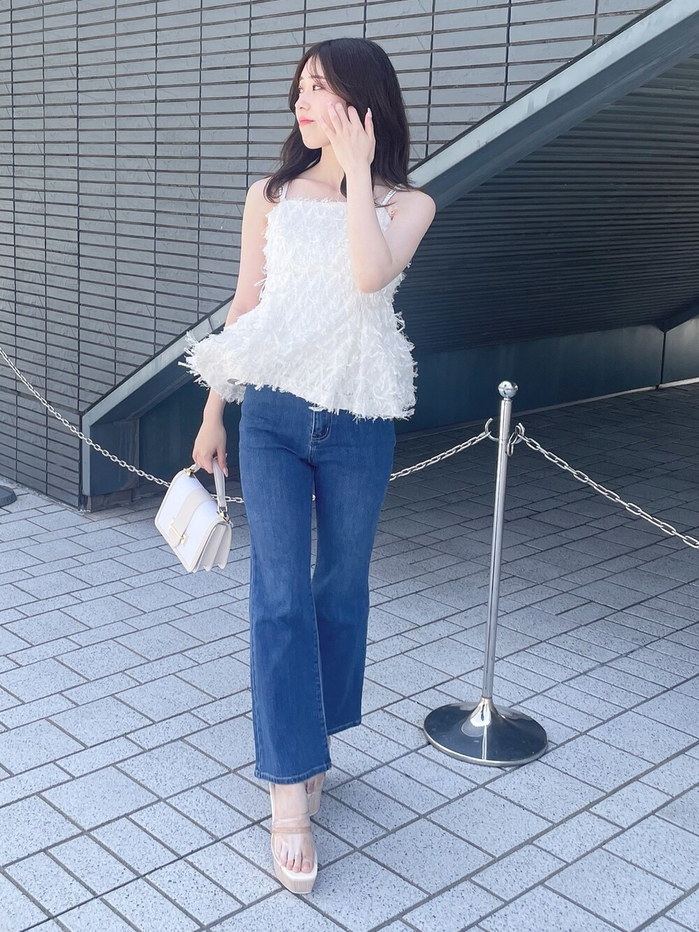 ホワイト系のキャミソール、ブルー系のデニムパンツ、その他のサンダルを着用したレディースの春コーディネートの3枚目の写真