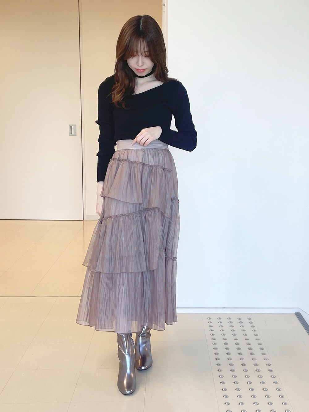 ゴールド系のブーツ、ブラウン系のスカート、ブラック系のニット/セーターを着用したレディースの冬コーディネートの3枚目の写真