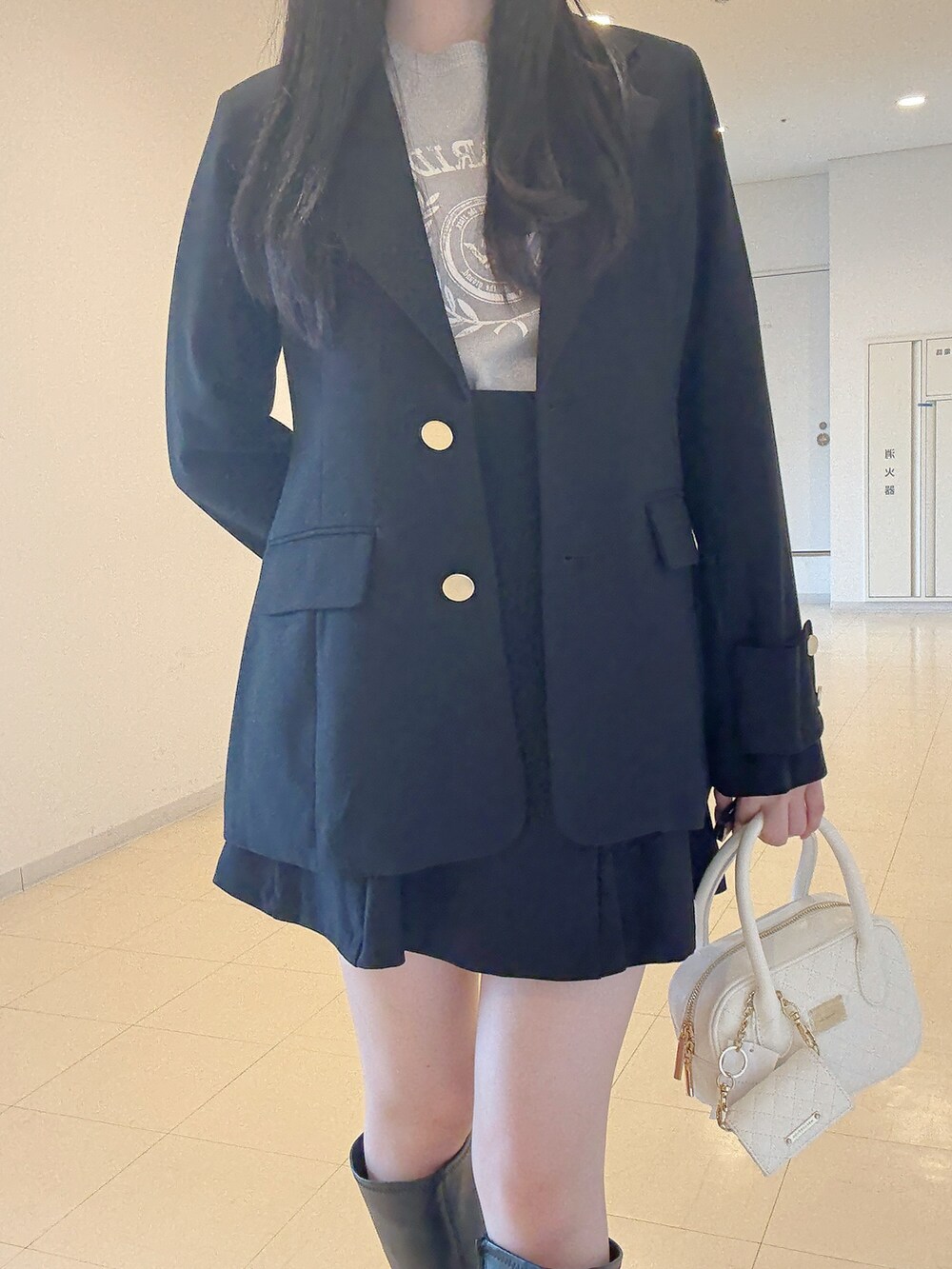 ブラック系のテーラードジャケット、グレー系のニット/セーター、ブラック系のスカートを着用したレディースの秋コーディネートの6枚目の写真